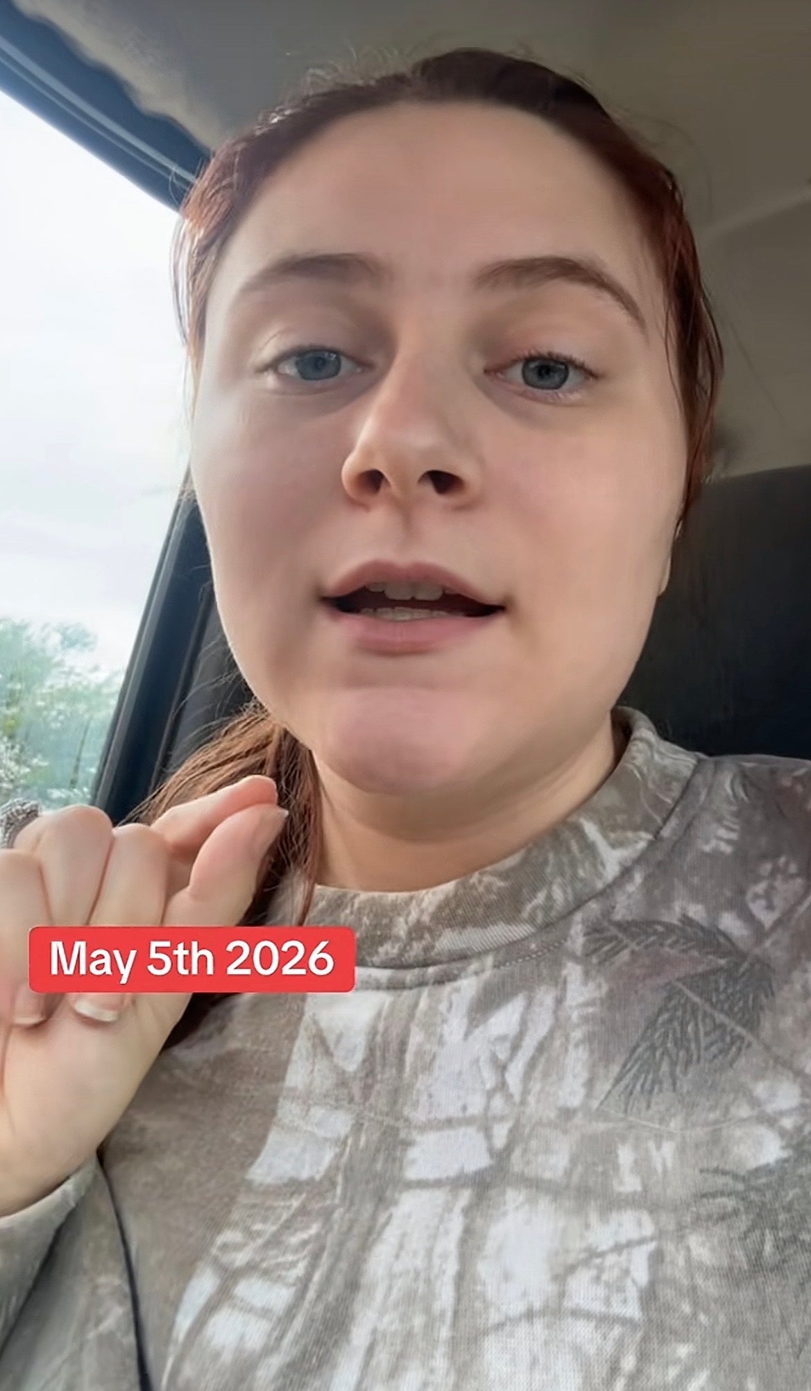 Person in a casual setting speaks into the camera, wearing a camouflage patterned sweatshirt. Text on image reads "May 5th, 2026."