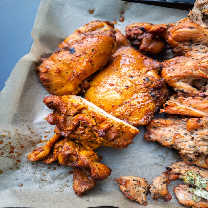 Grilled chicken pieces on parchment paper. The chicken has a seasoned, roasted appearance, showcasing crispy edges