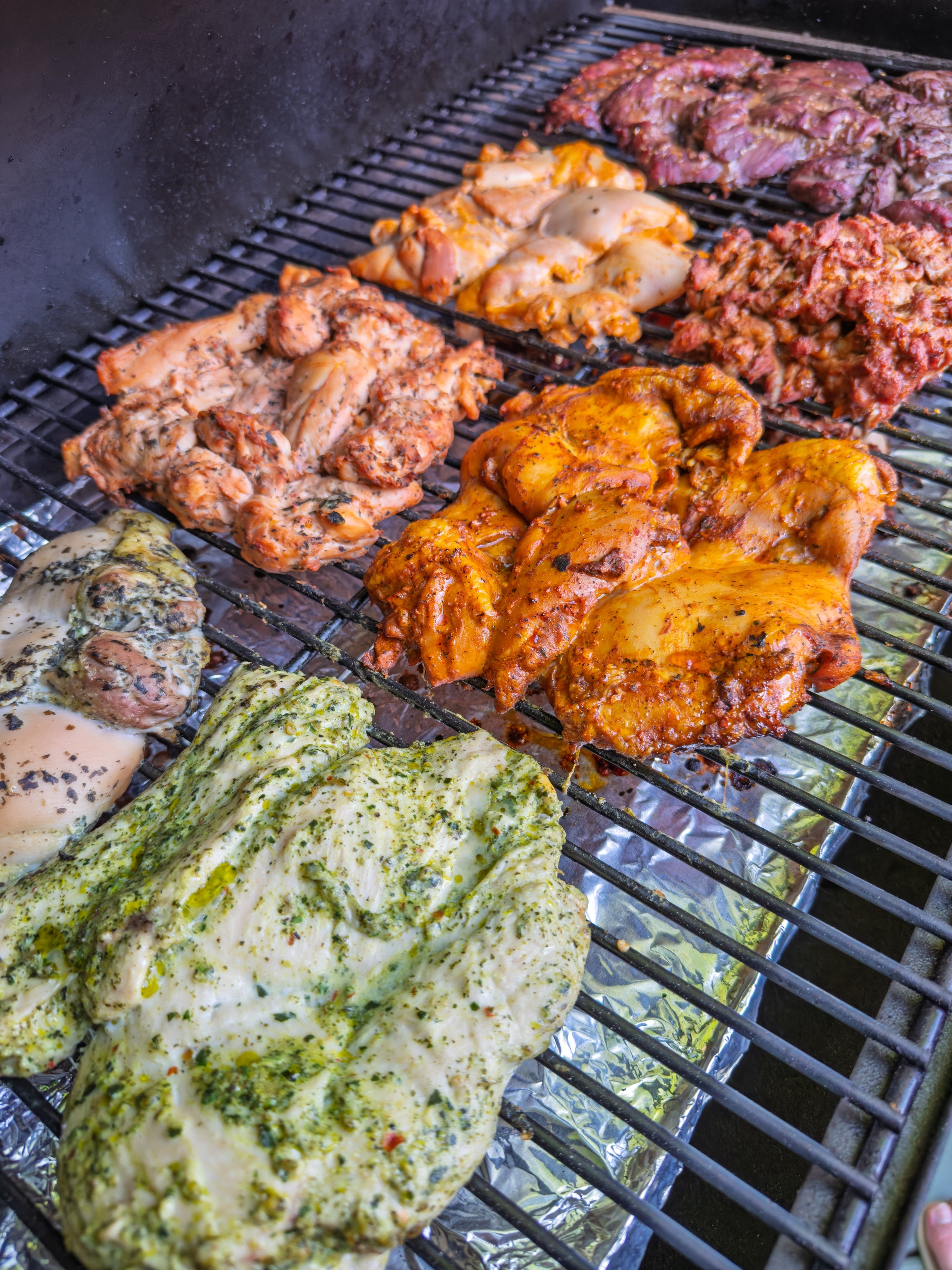 Various marinated chicken pieces grilling on a barbecue, showcasing diverse textures and seasonings