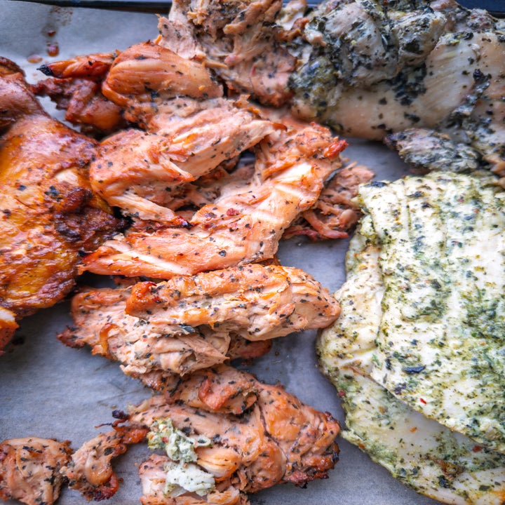 Assorted seasoned grilled chicken pieces on parchment paper