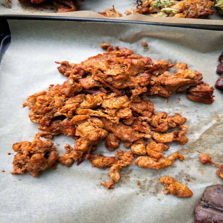 Cooked, shredded meat pieces on parchment paper