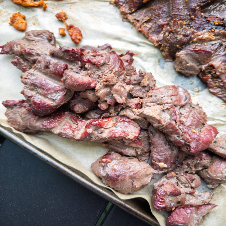 Cooked pieces of sliced beef on parchment paper, showing a variety of textures and doneness