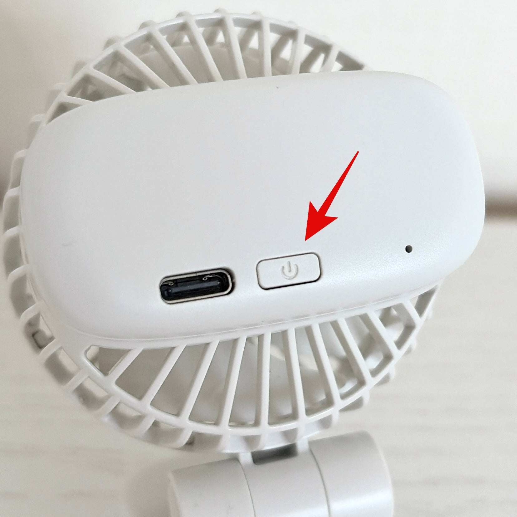 無印良品「置いても使える 充電式クリップファン ミニ」白い携帯ファンの電源ボタン部分を示した画像。