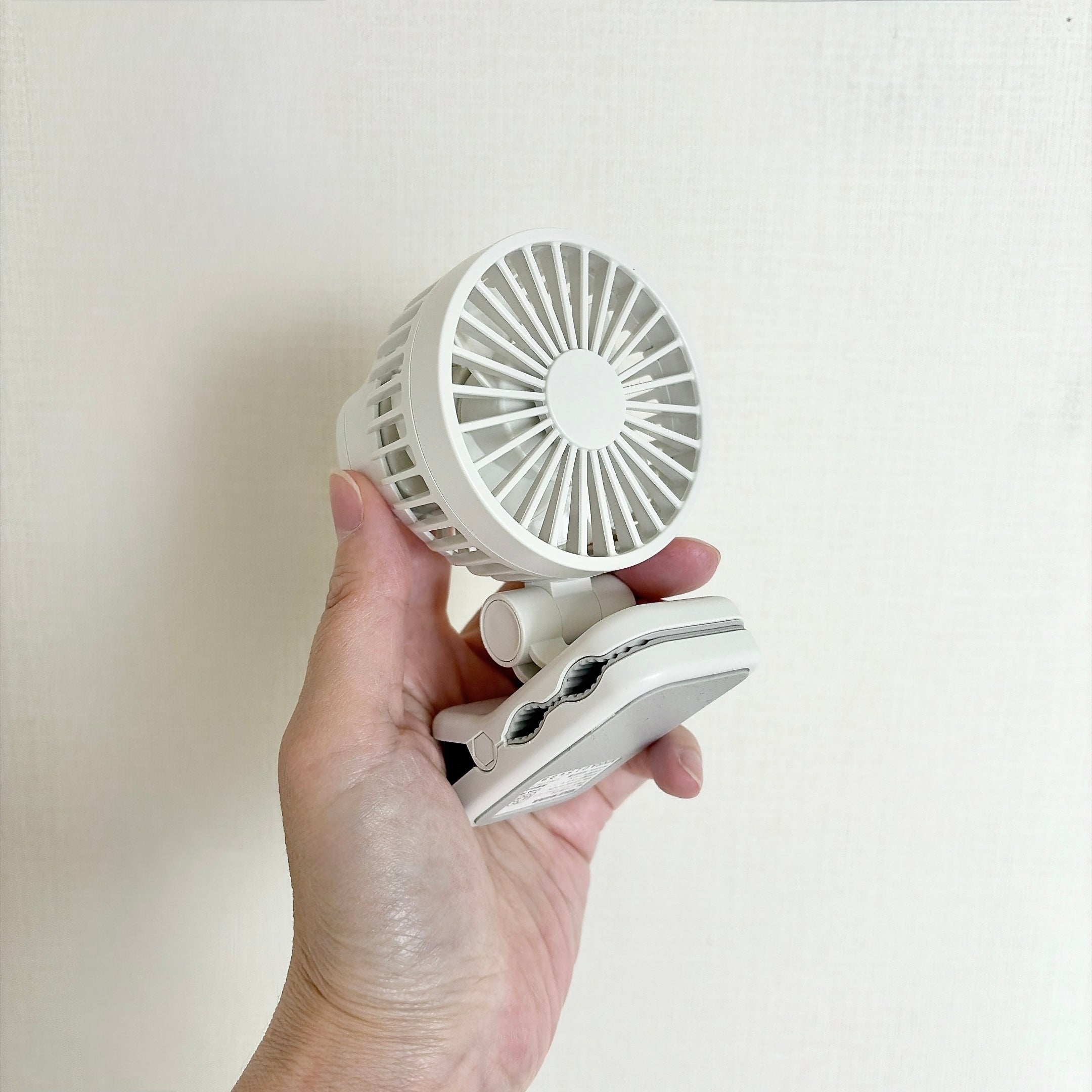 無印良品「置いても使える 充電式クリップファン ミニ」手に持たれた小型のクリップ式扇風機。