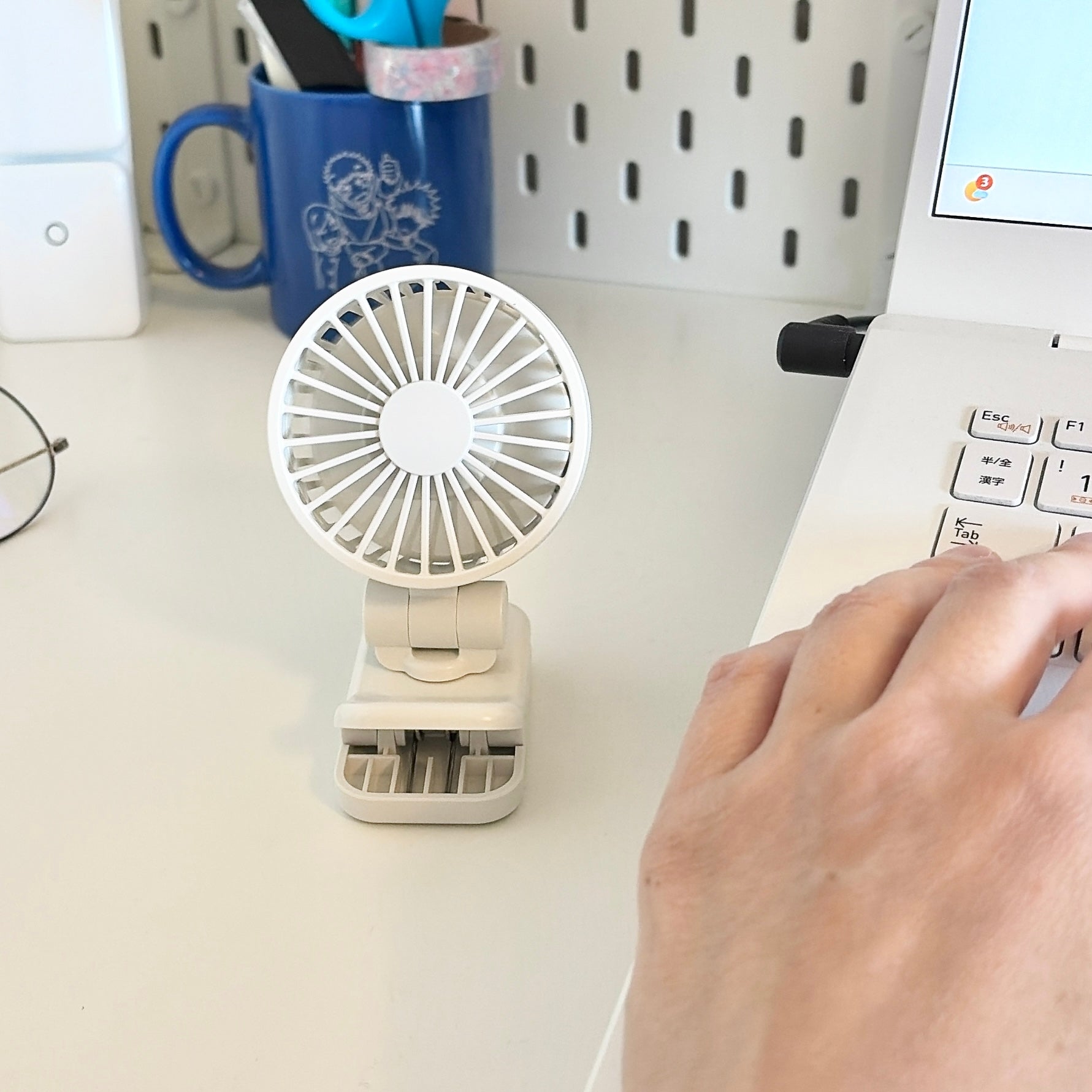 無印良品「置いても使える 充電式クリップファン ミニ」デスク上の小型扇風機と手元のノートパソコンで作業している様子。