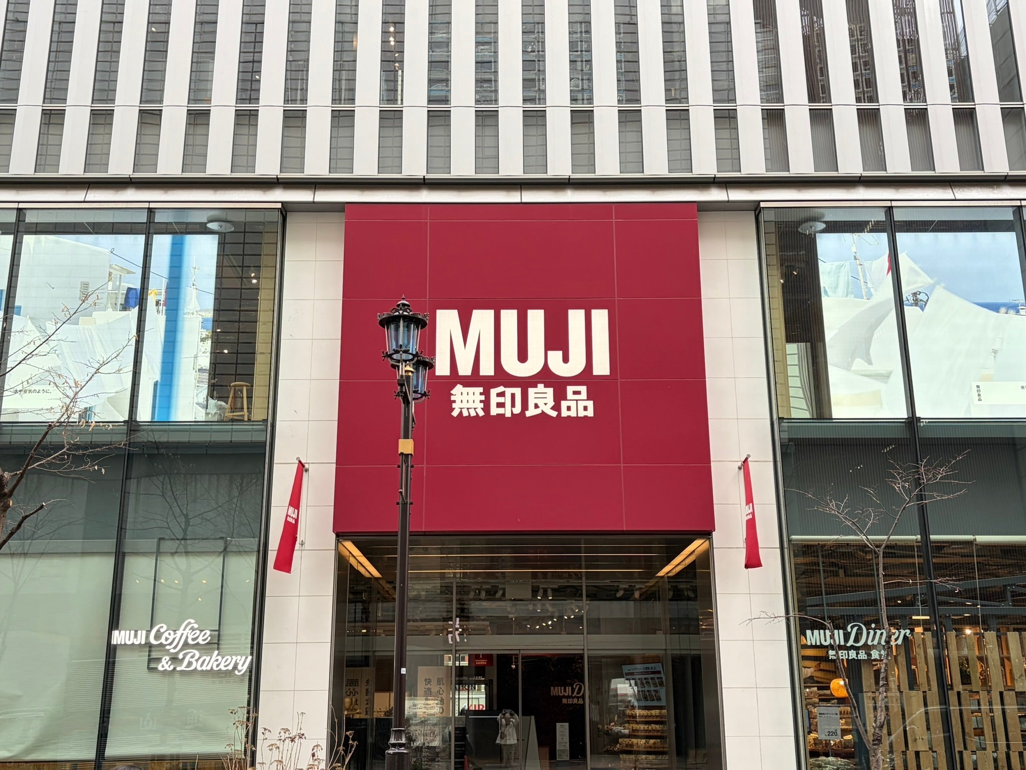 MUJIの店舗外観。看板には「無印良品」と記載され、入口には「MUJI Coffee & Bakery」と表示があります。