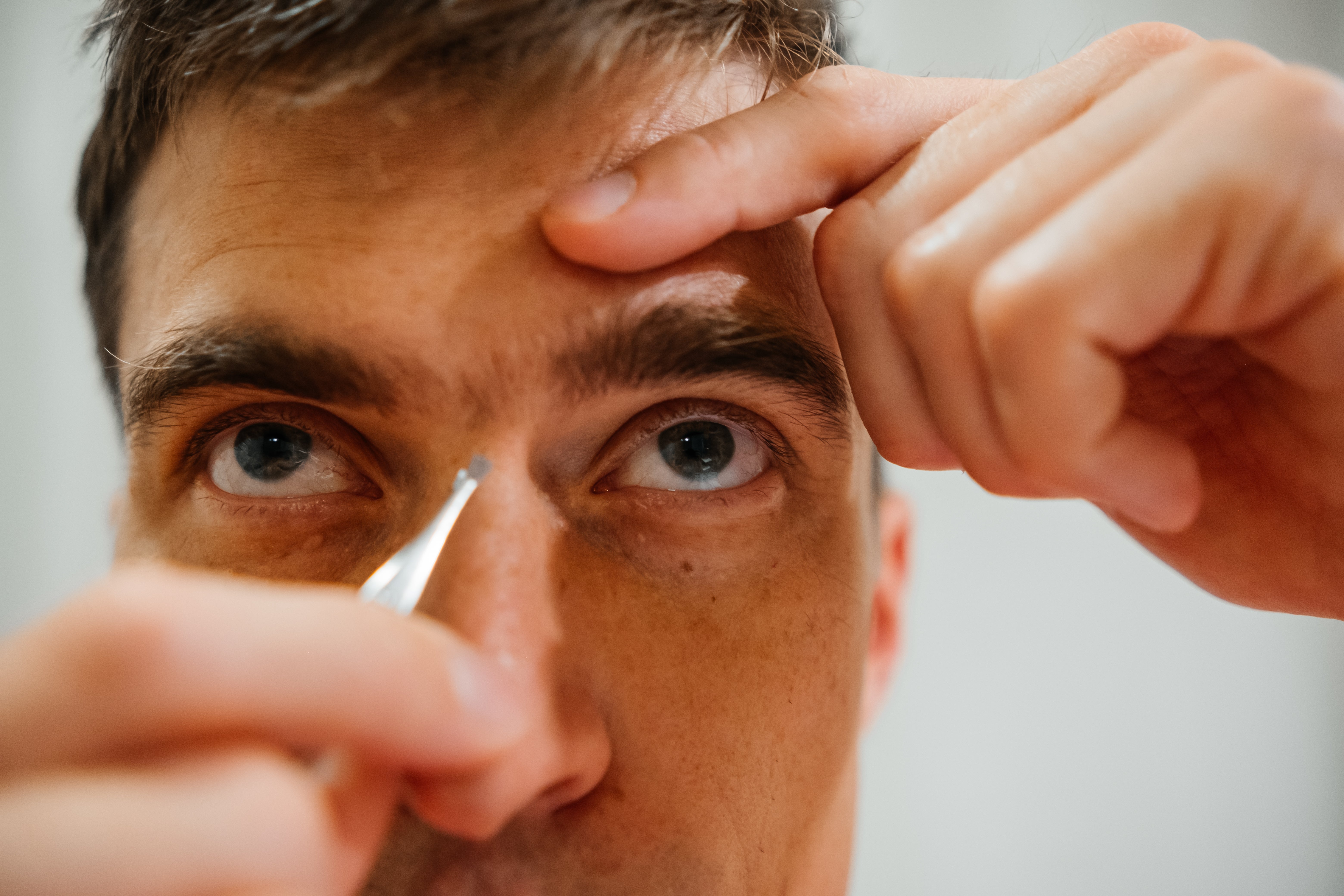 A person tweezing their eyebrows