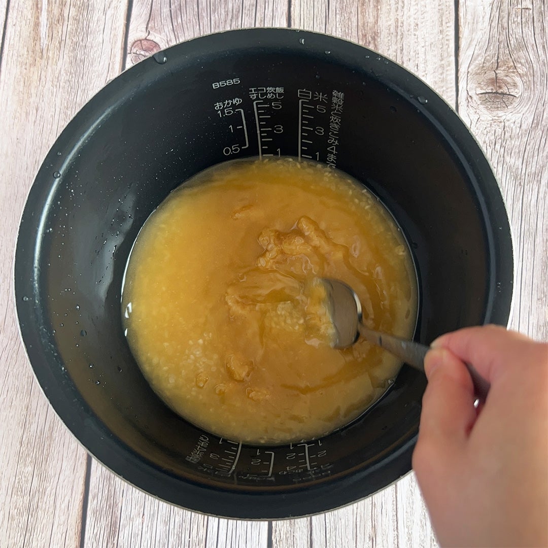 炊飯器の内釜をスプーンでかき混ぜている。