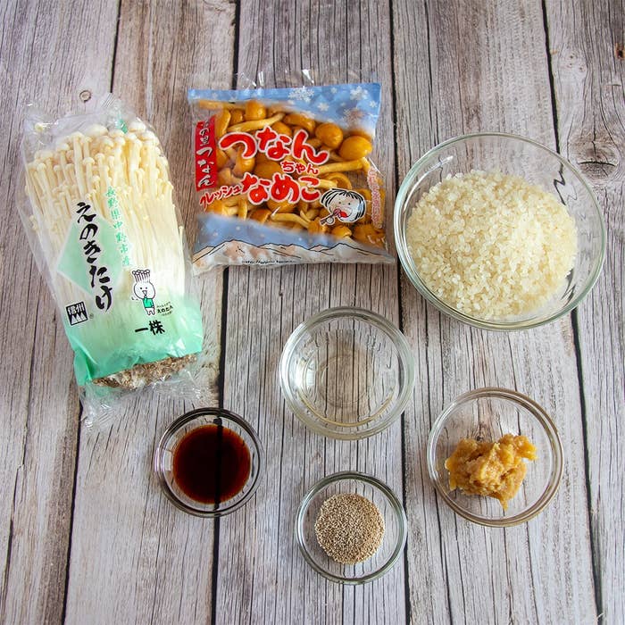 木のテーブルに並べられたえのき、なめこ、米、調味料の小皿。