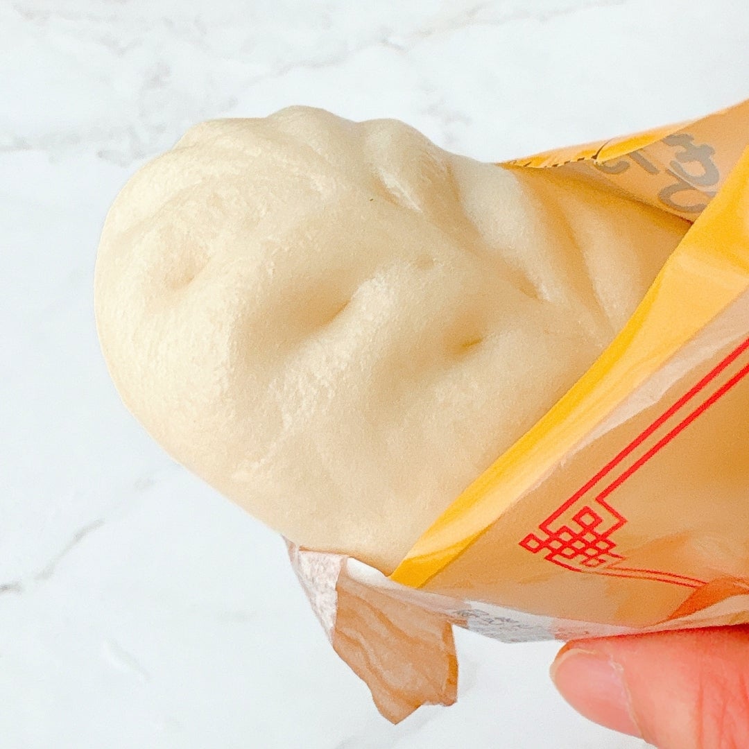 ミニストップの「餃子ドッグ」を手に持っている様子。包装紙に包まれています。