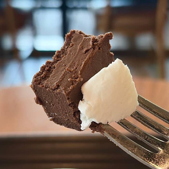 スタバ「チョコレートテリーヌ」フォークに刺さったチョコレートケーキの一切れとクリームのクローズアップ。