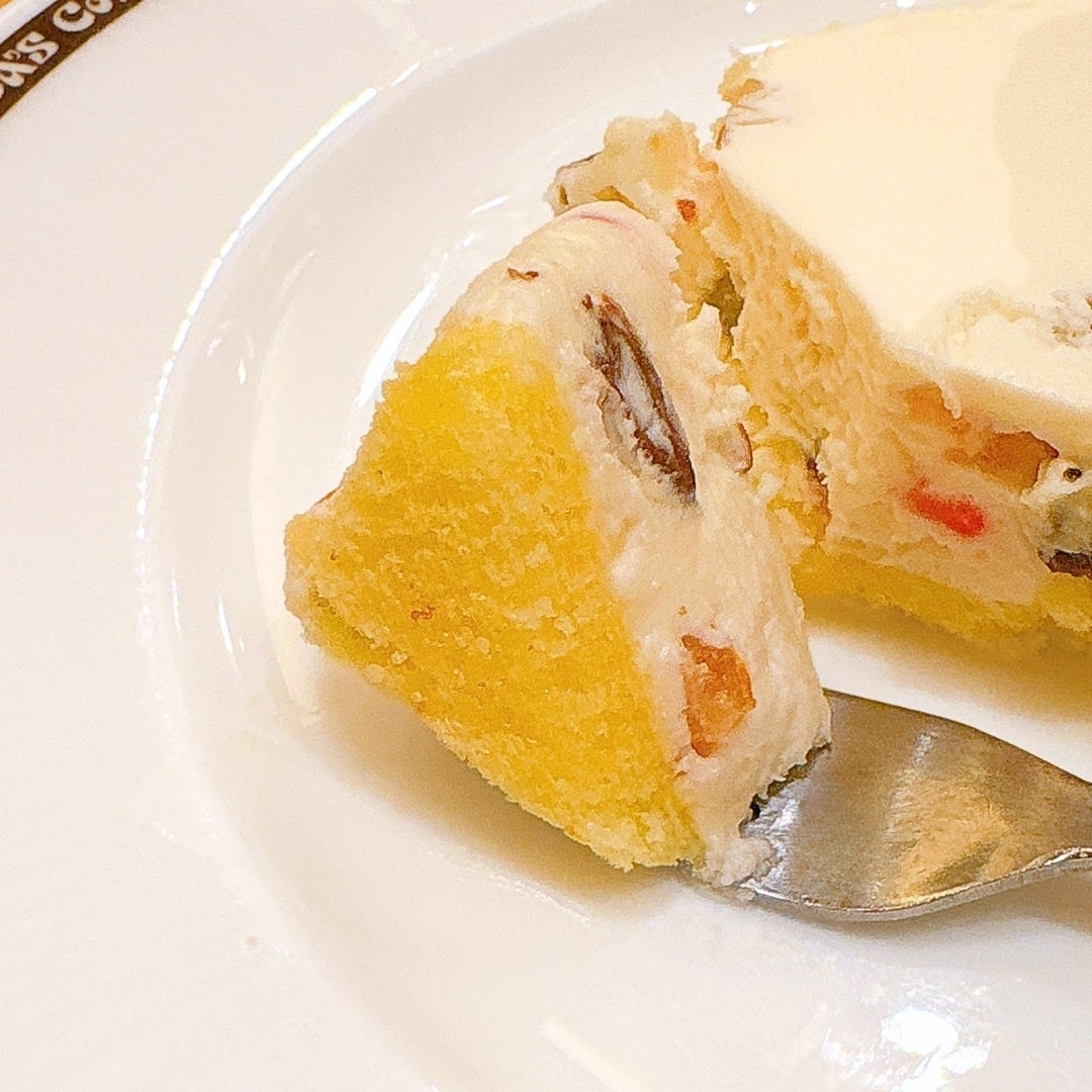 コメダ珈琲店「くちどけカッサータ」ケーキの一切れが皿に乗っており、フォークが添えられています。クリームとフルーツが見えます。