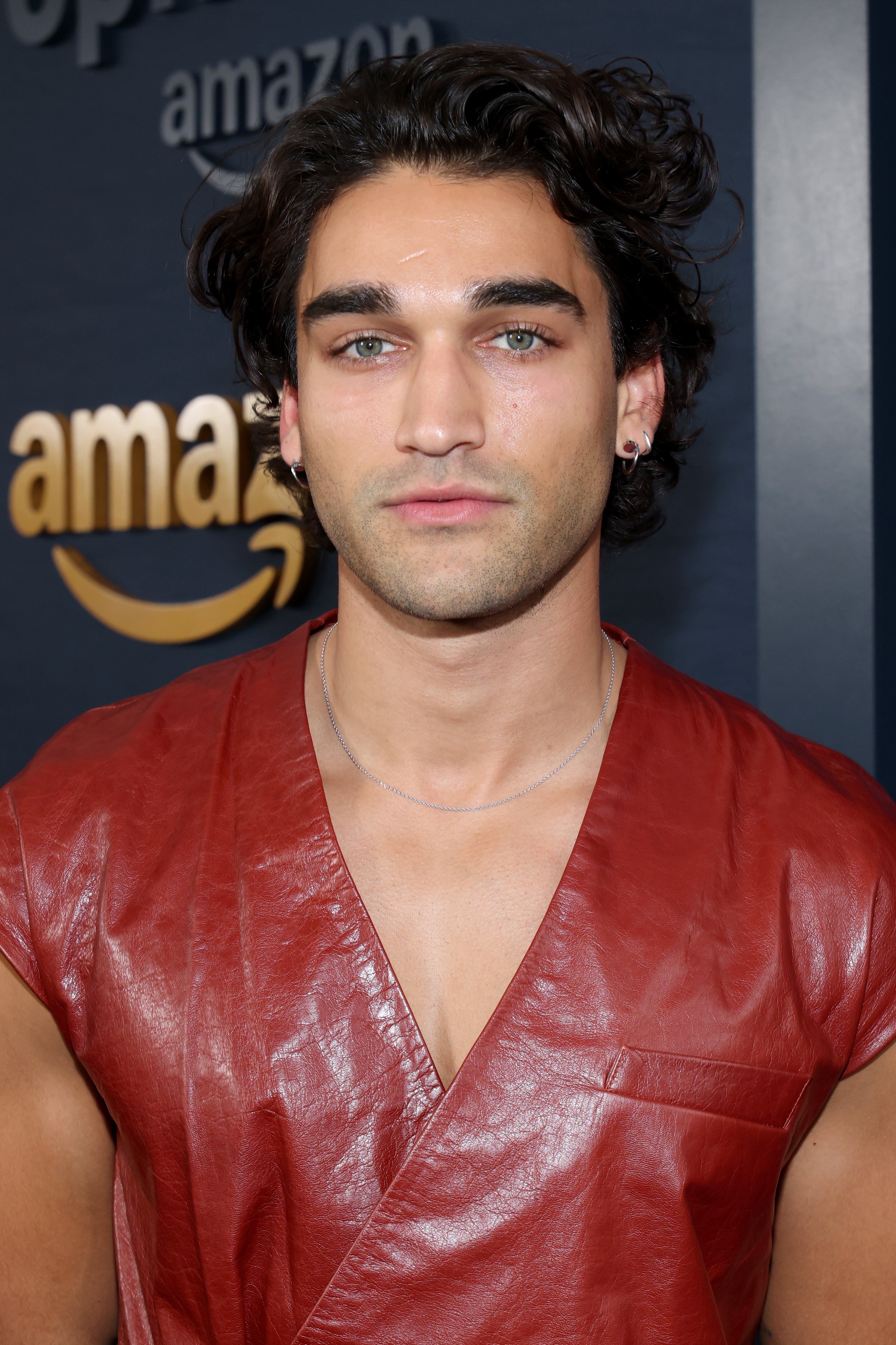Person in a red leather top at a media event, standing in front of an Amazon logo backdrop