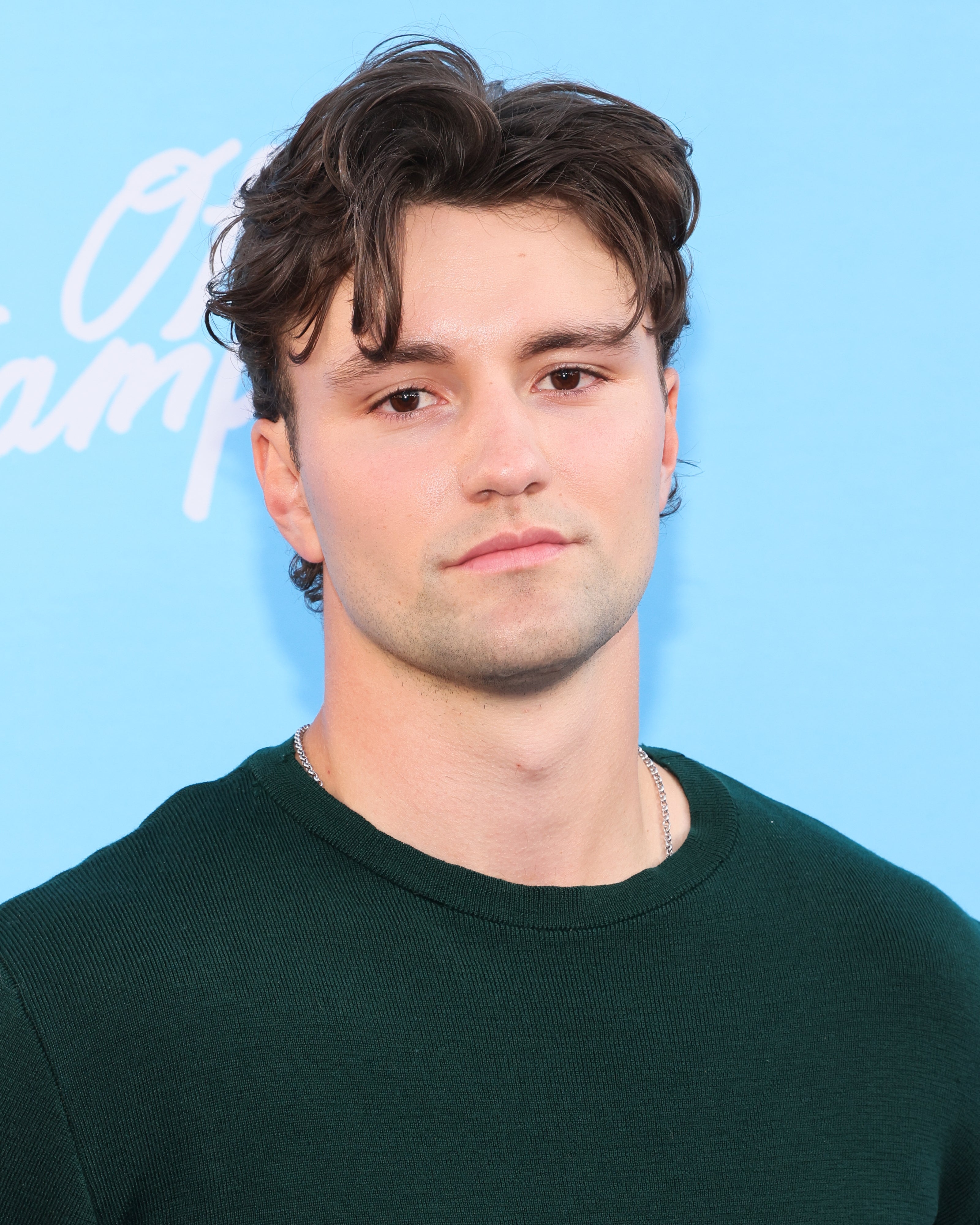 Person wearing a dark shirt, standing with a neutral expression against a plain background