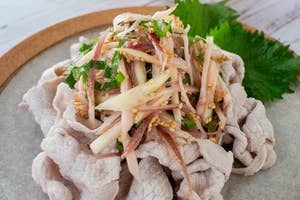 冷しゃぶサラダのイメージ。薄切り豚肉と野菜の盛り合わせが皿に美しく盛られ、後ろにはレモンのスライスが添えられている。