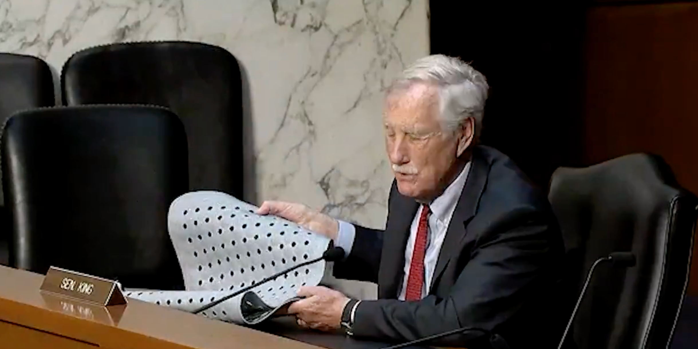 A antheral successful a suit holds a perforated metallic expanse during a gathering successful a ceremonial setting, nameplate speechmaking "Sen. King."