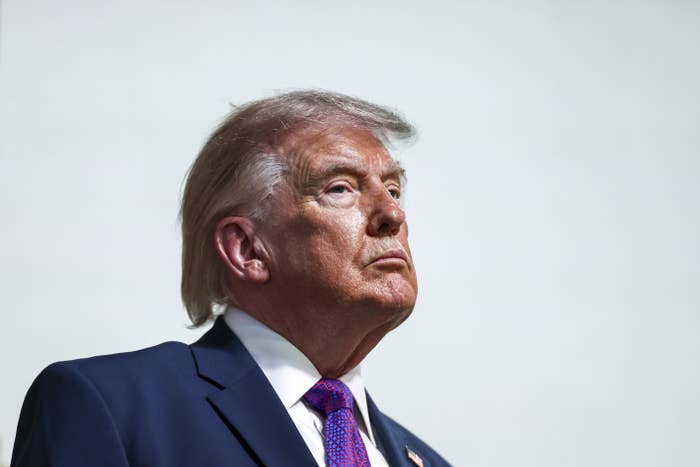 A person in a suit and tie looks upward with a serious expression