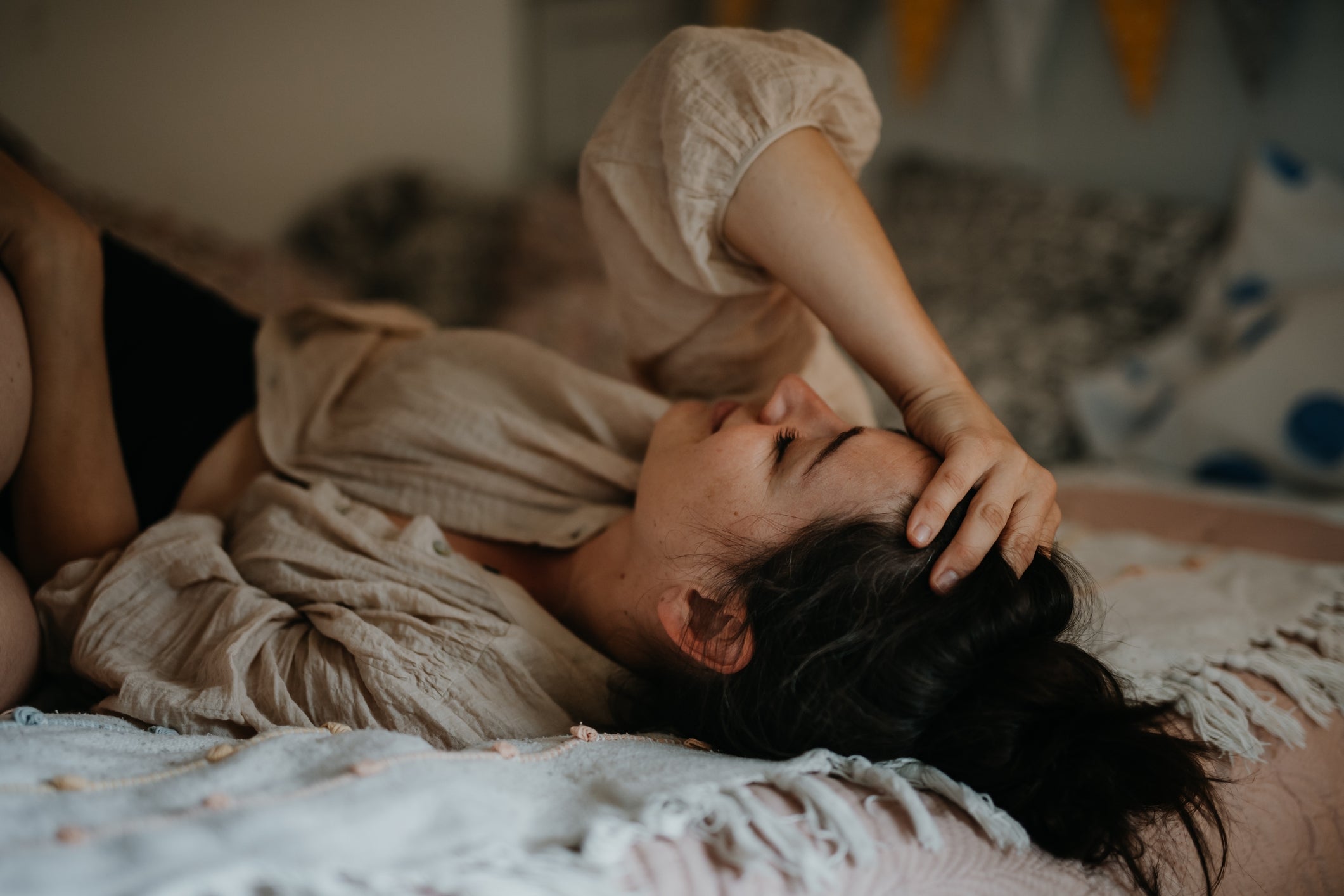 Person lying on a bed, appearing relaxed or thoughtful, with a hand resting on their head. The setting suggests a calm, private moment