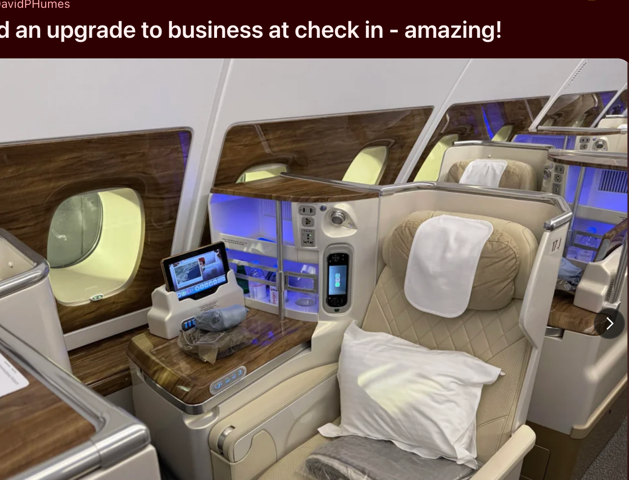 Airplane business class seat with luxurious amenities and screen displays. Reddit post about upgrade to business class at check-in