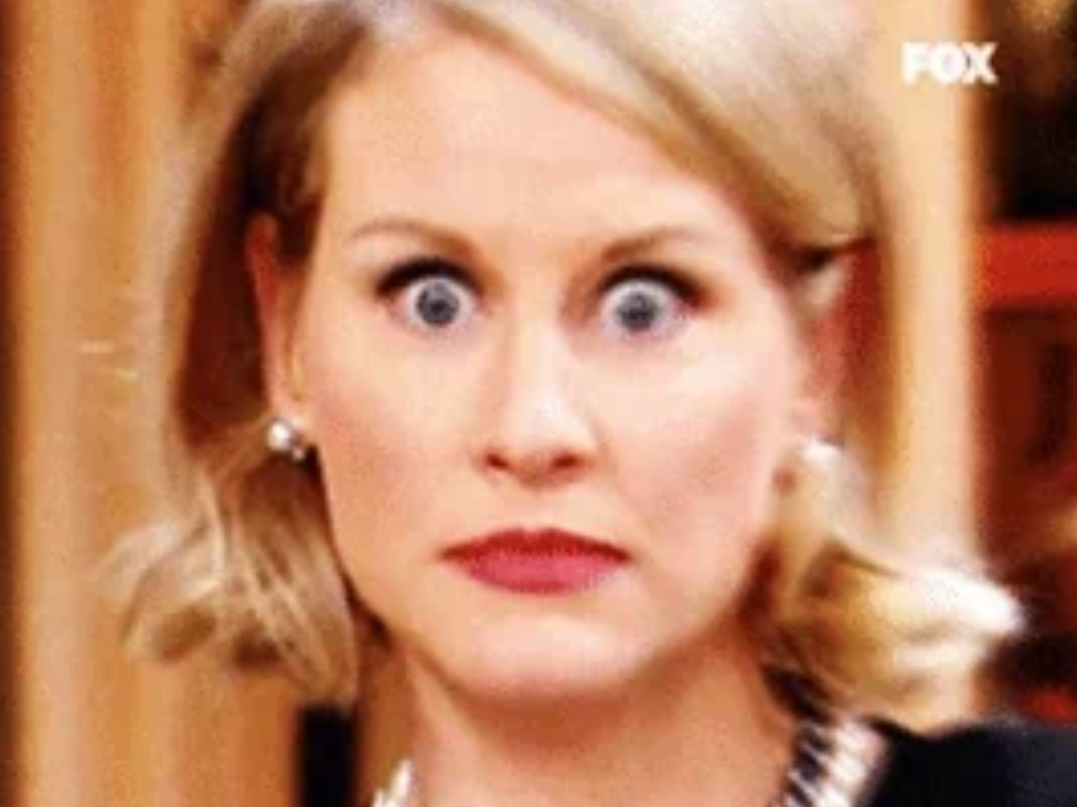 A surprised woman with wide eyes and earrings. The expression suggests shock or disbelief, possibly related to a work or financial situation