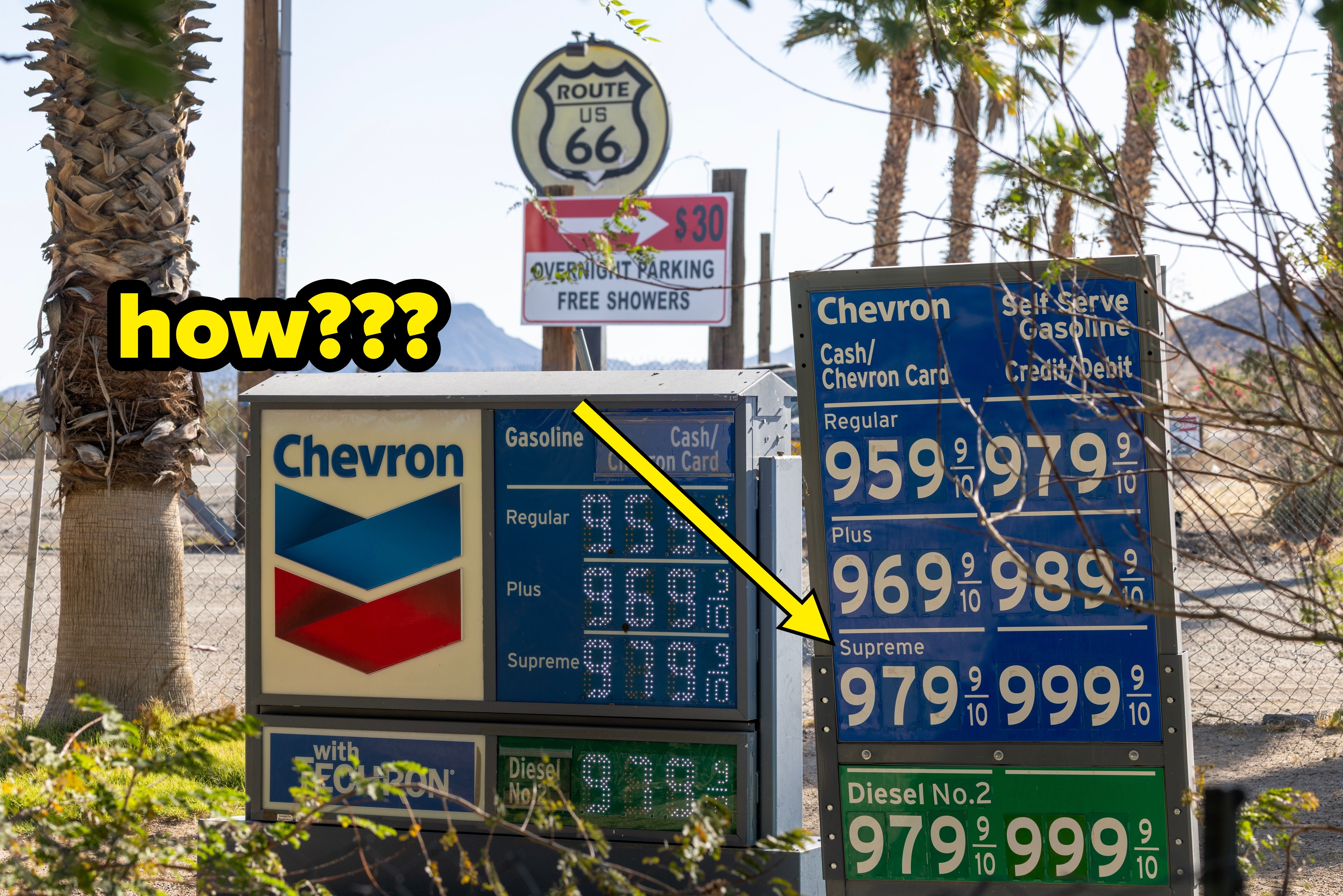 Gas station sign displaying fuel prices near a Route 66 sign, with palm trees and mountains in the background