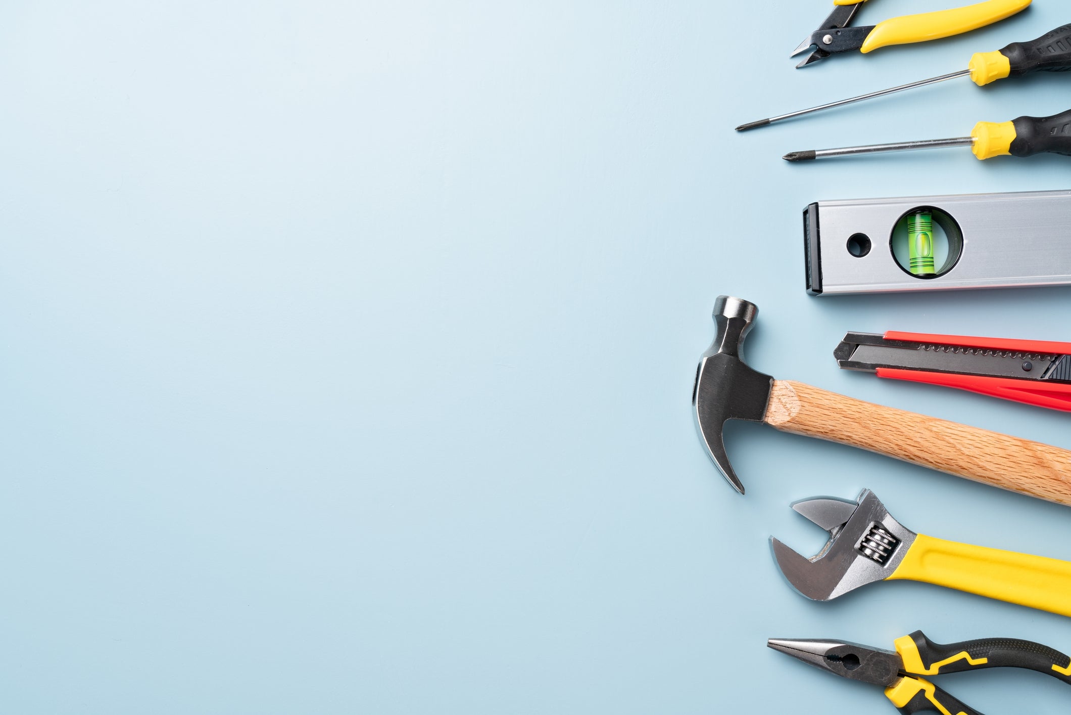 Various manus tools, including a hammer, screwdriver, and wrench, are neatly arranged connected a surface