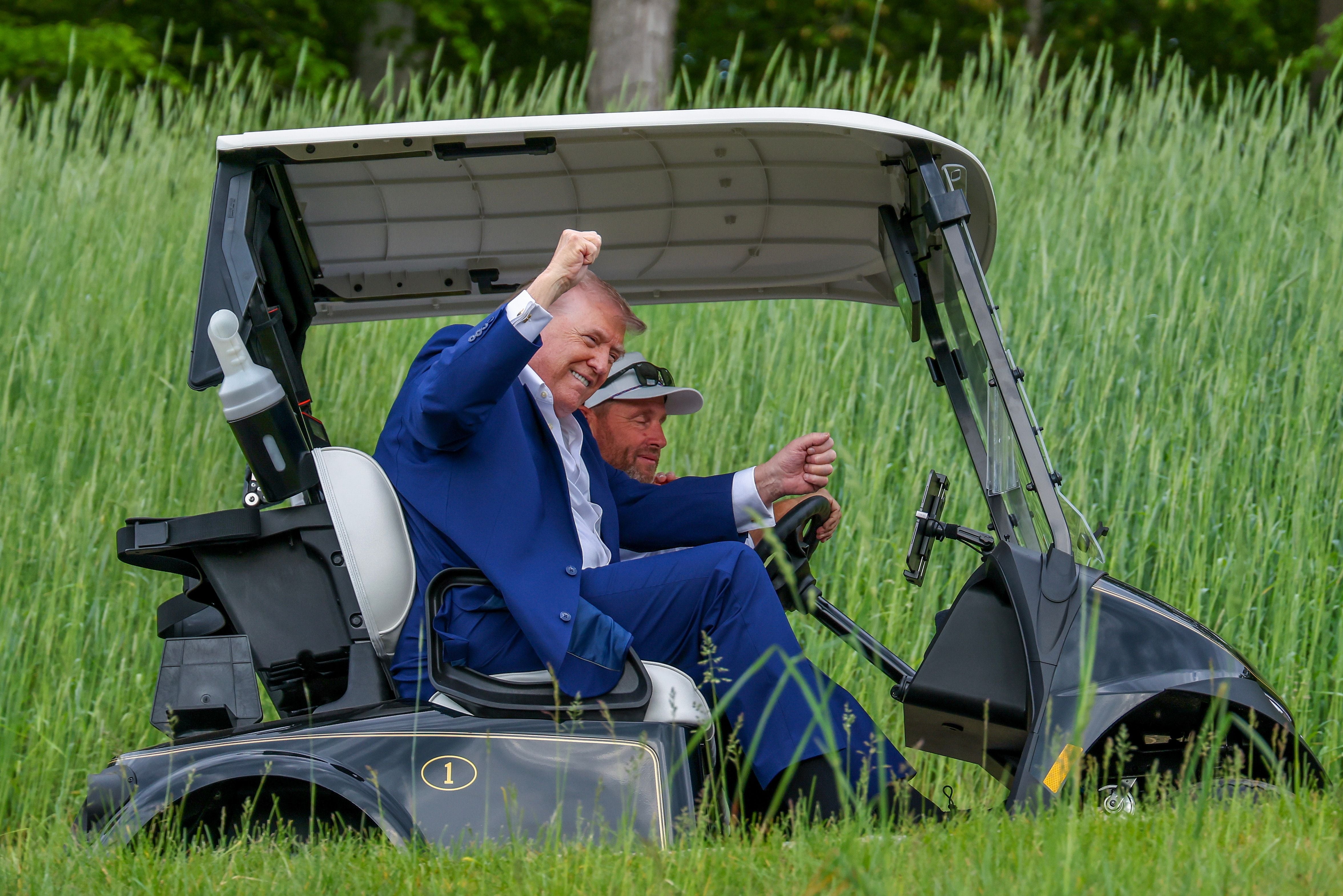 Two men successful  a play  cart, 1  wearing a suit, raising a fist successful  celebration. Tall writer  surrounds the cart