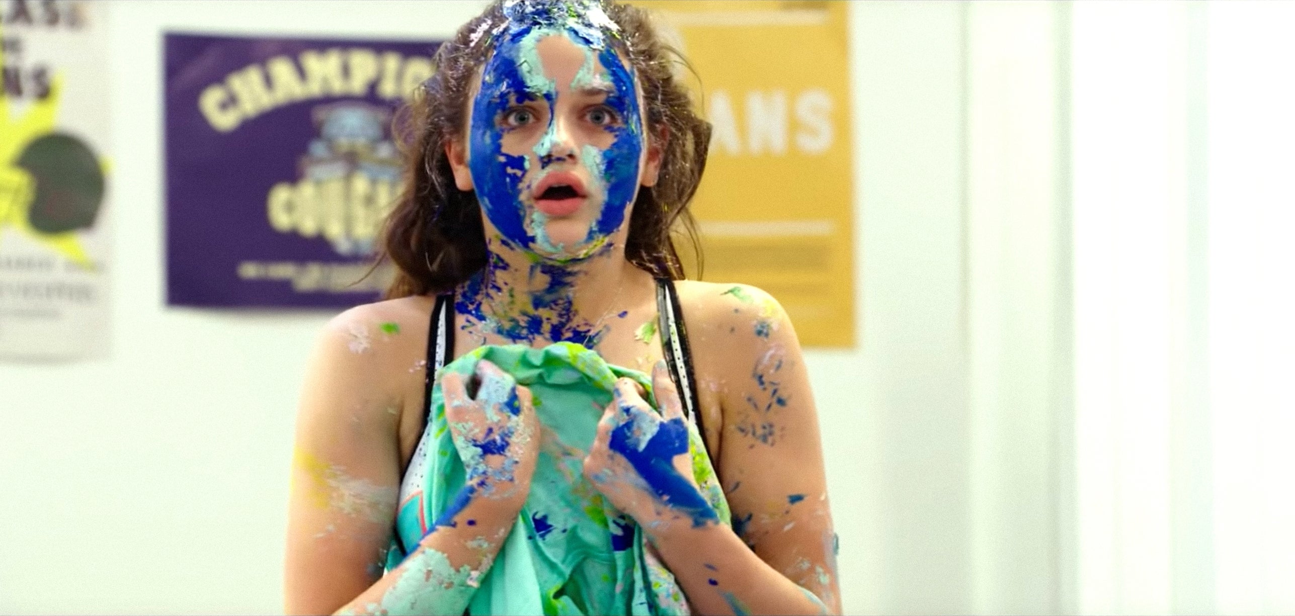 Person surprised, covered successful bluish and yellowish paint, lasting successful a country with posters connected the wall