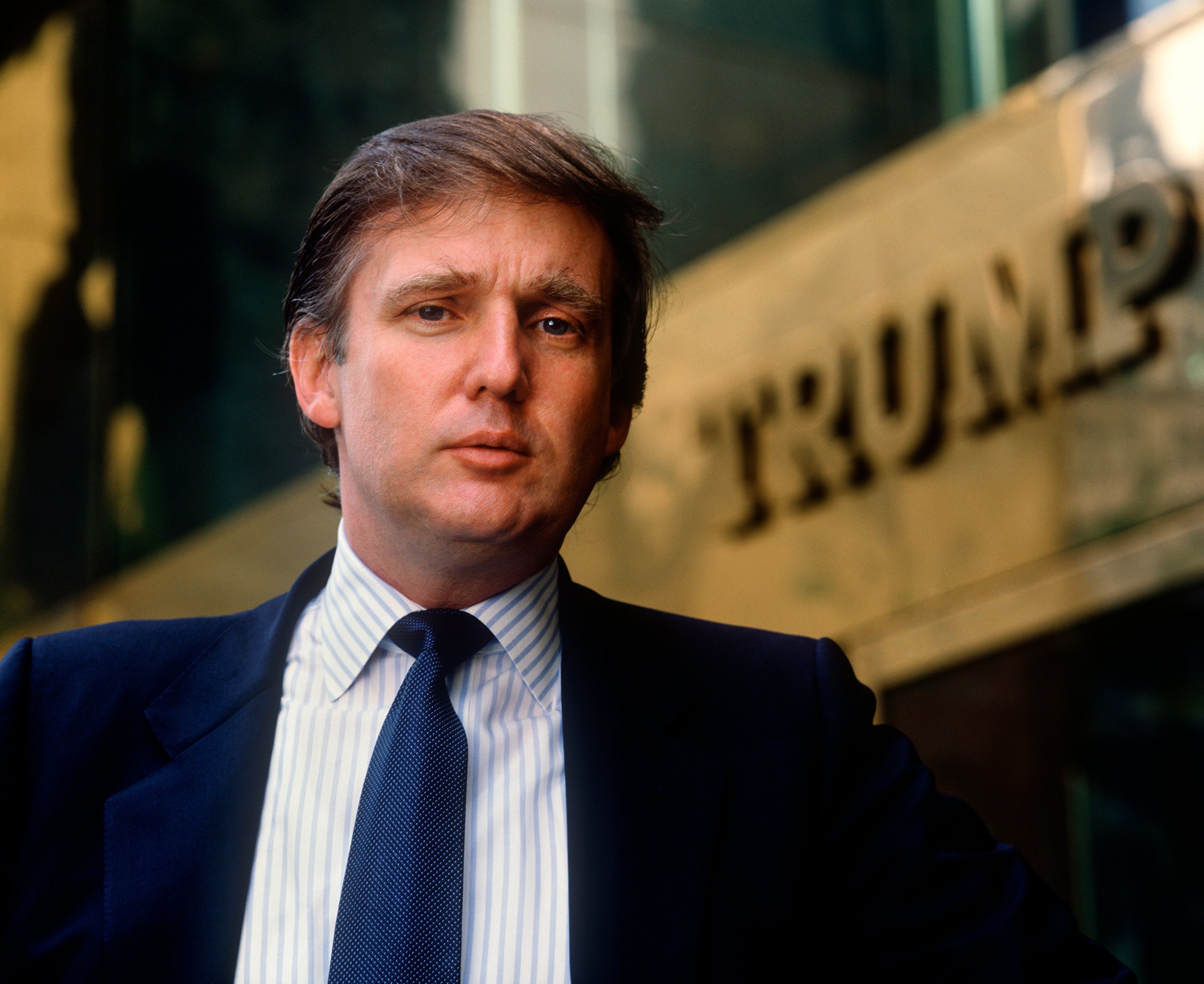 Man successful a suit stands successful beforehand of a gathering with "TRUMP" signage visible