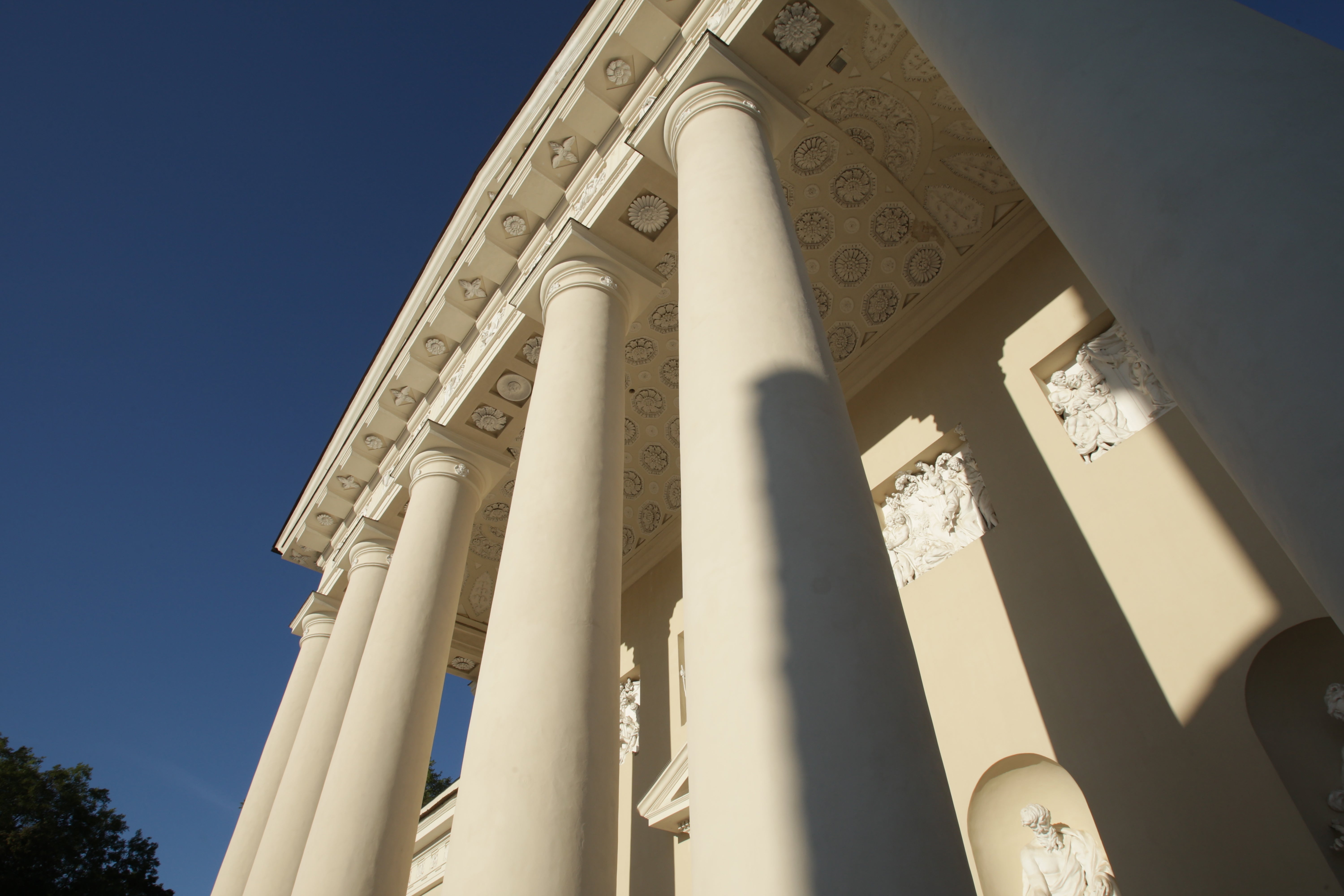 Neoclassical gathering with ornate columns and elaborate architectural sculptures, viewed from a debased angle