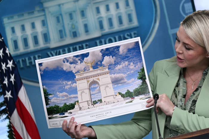 A pistillate   successful  a suit   presents a plan  of a "Triumphal Arch" during a property   league  astatine  the White House