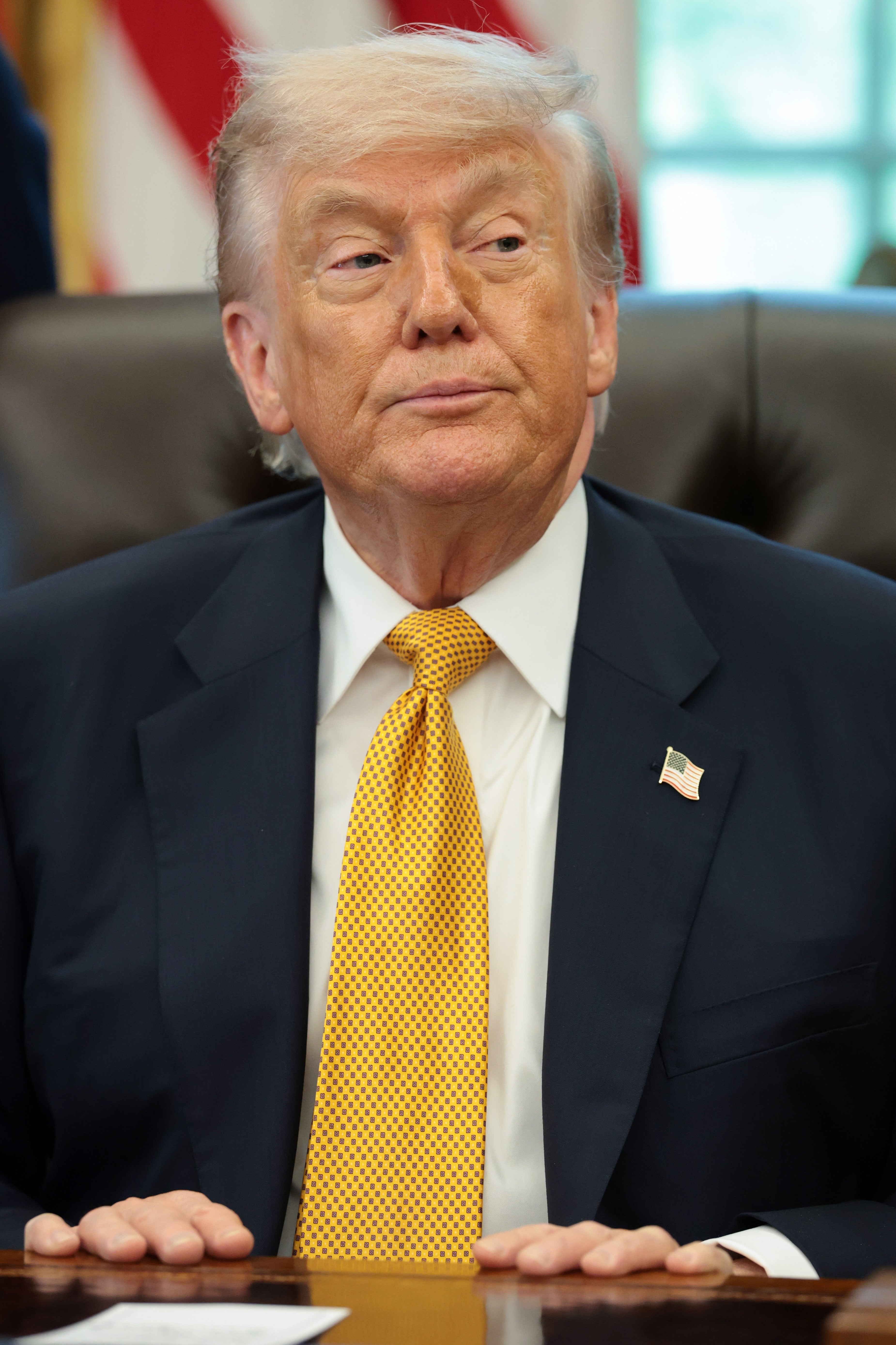 A idiosyncratic successful a suit with a polka dot necktie sits astatine a table successful an bureau setting, looking disconnected to the side
