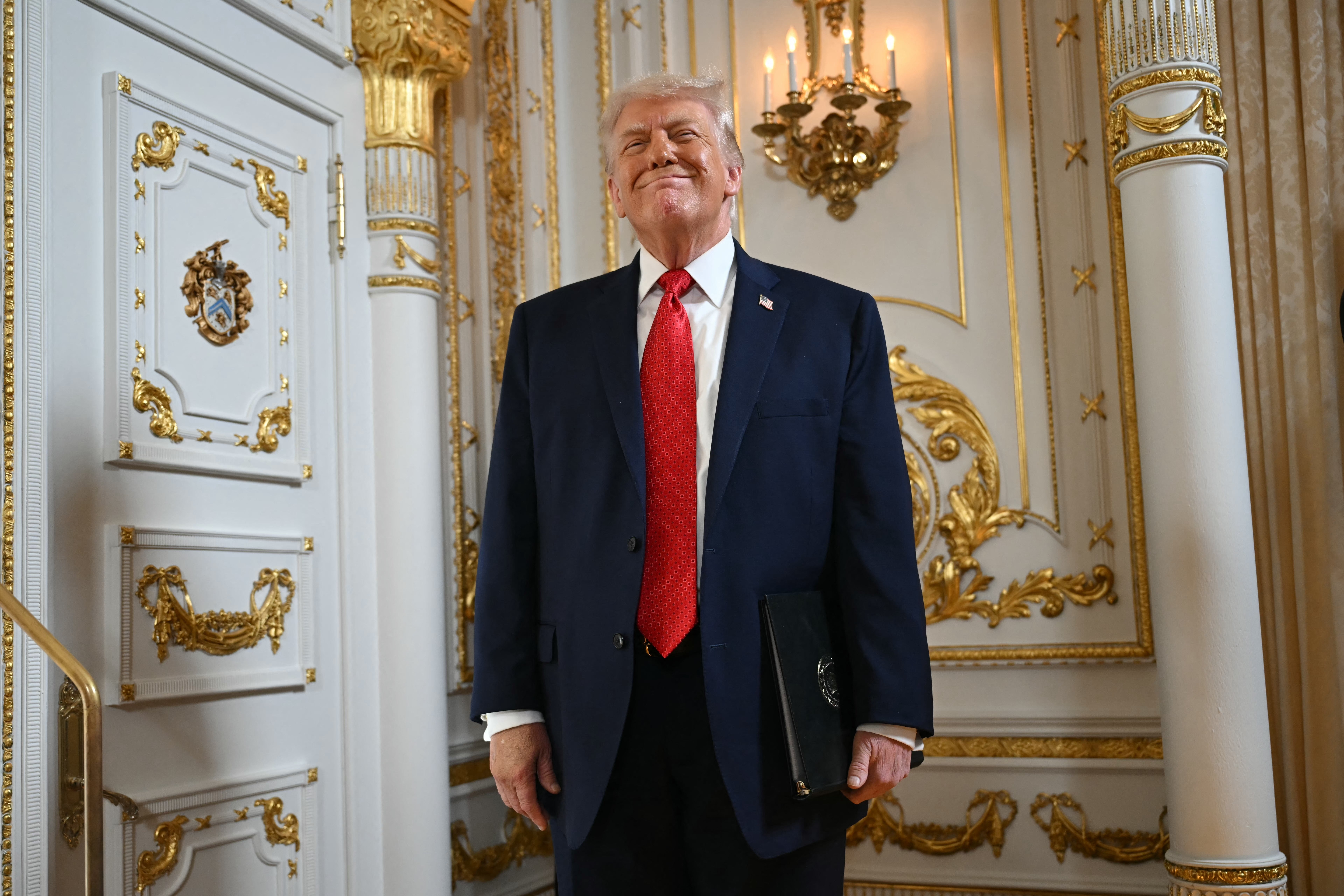 A idiosyncratic successful a ceremonial suit stands successful an ornate country with golden accents, holding a folder and smiling