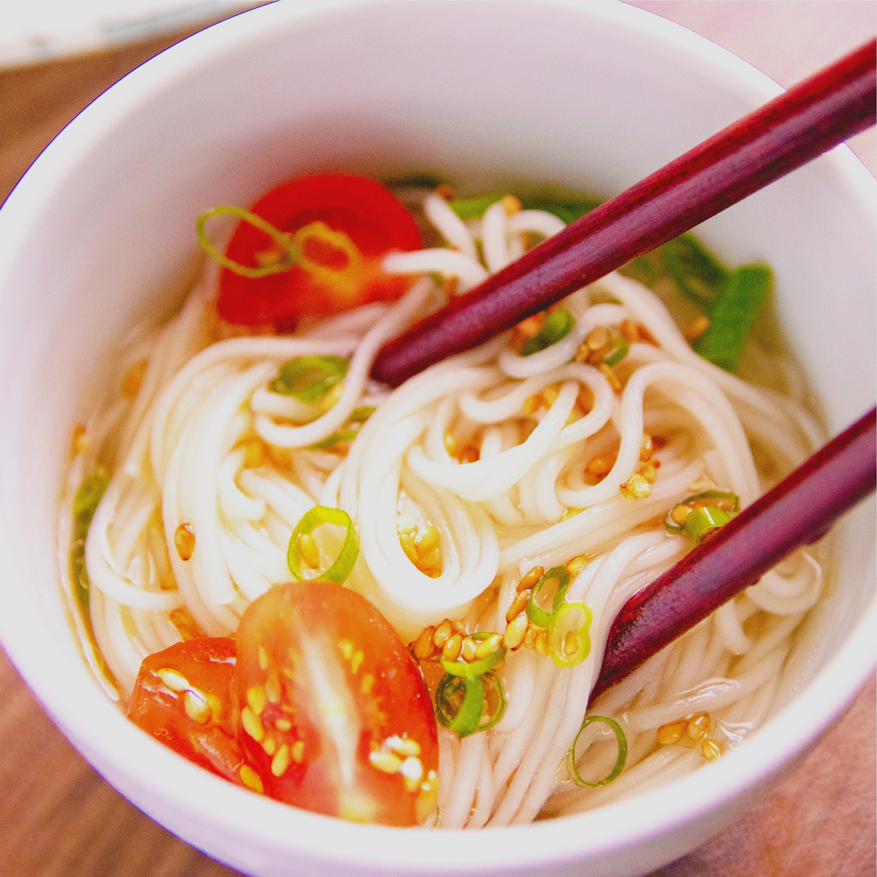 完成した白だしそうめんに箸がつけられている様子。具材のミニトマトや小ねぎがきれいに盛り付けられている。