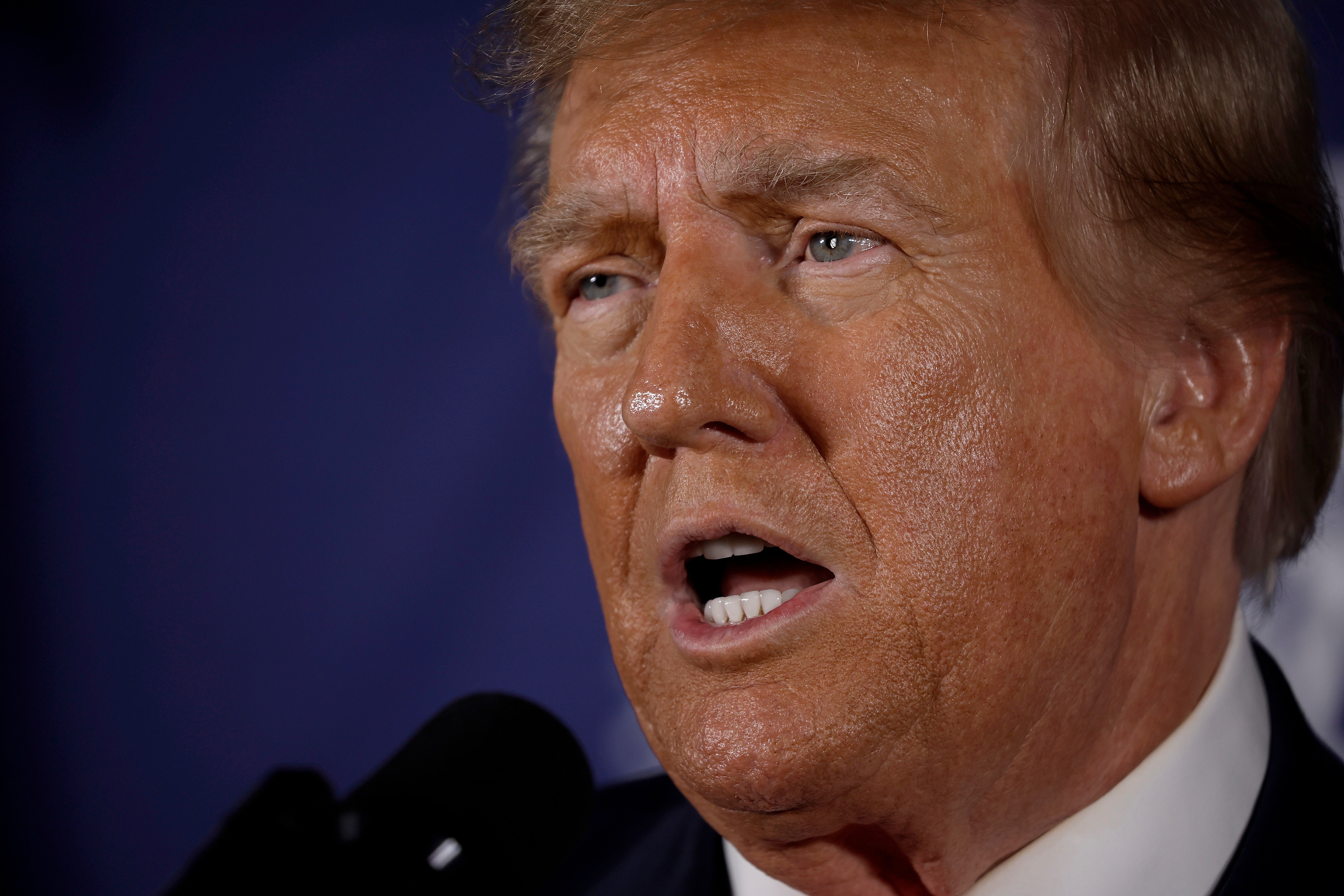 A idiosyncratic speaking successful beforehand of a microphone, captured successful a close-up shot, appearing engaged successful a nationalist address