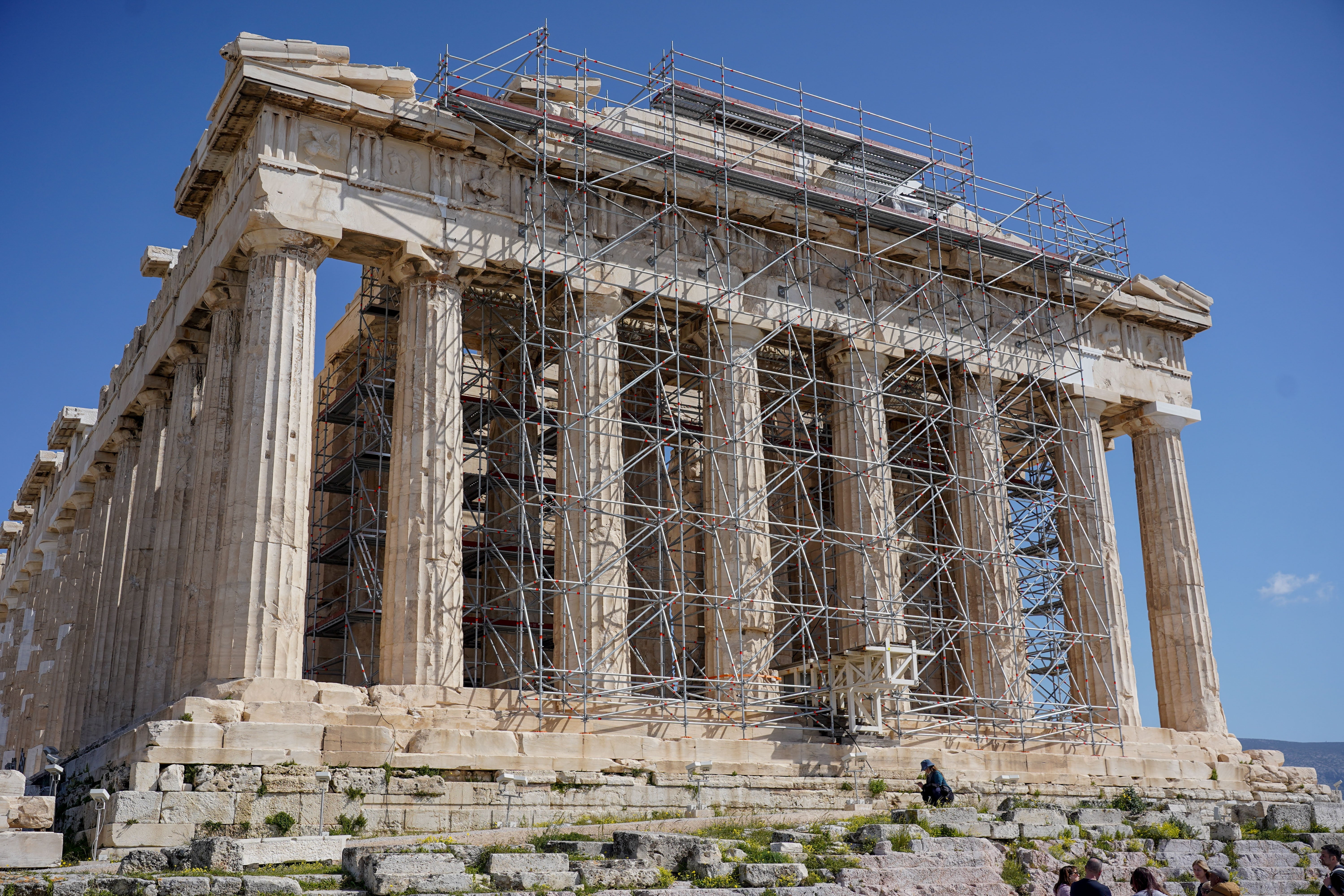 Ancient Greek Parthenon undergoing restoration with scaffolding crossed columns, acceptable against a wide sky