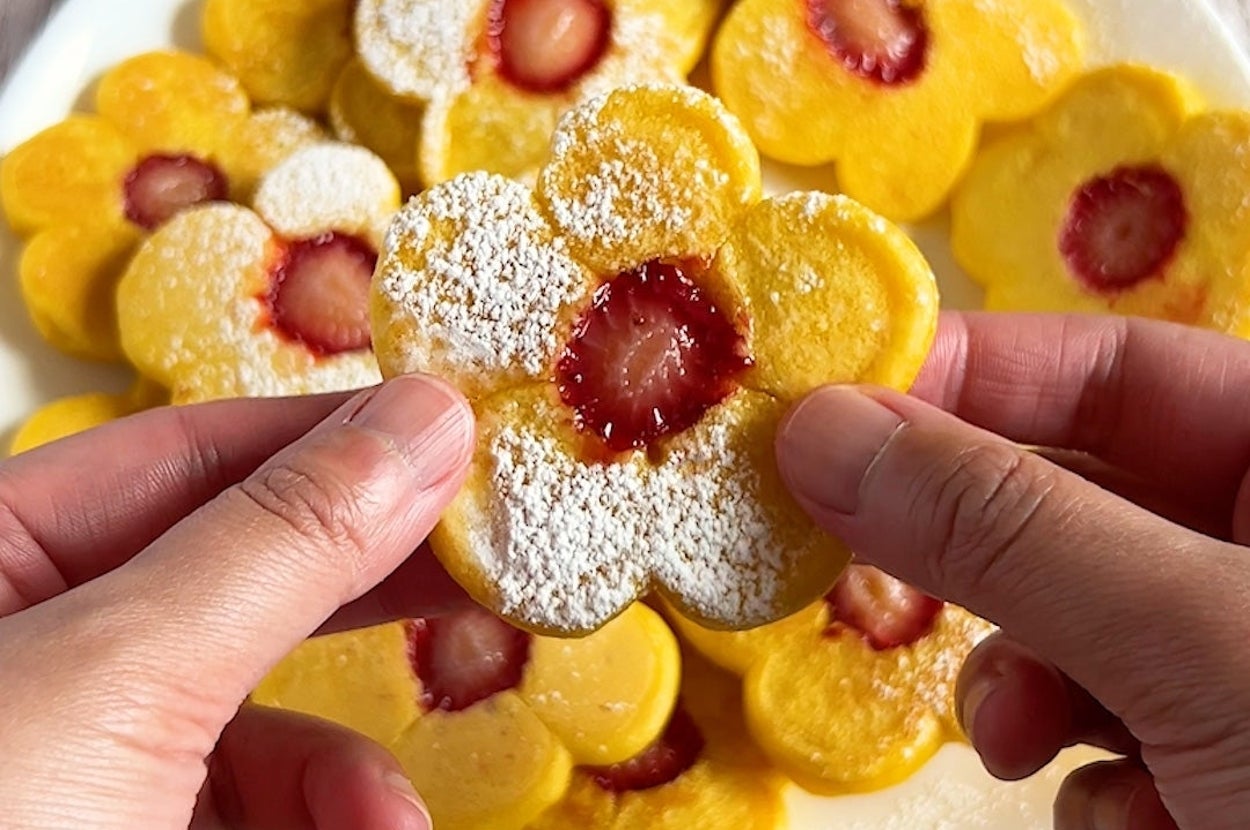 花形のパンケーキを手に持つ。中心にイチゴがのっており、粉砂糖が振りかけられている。