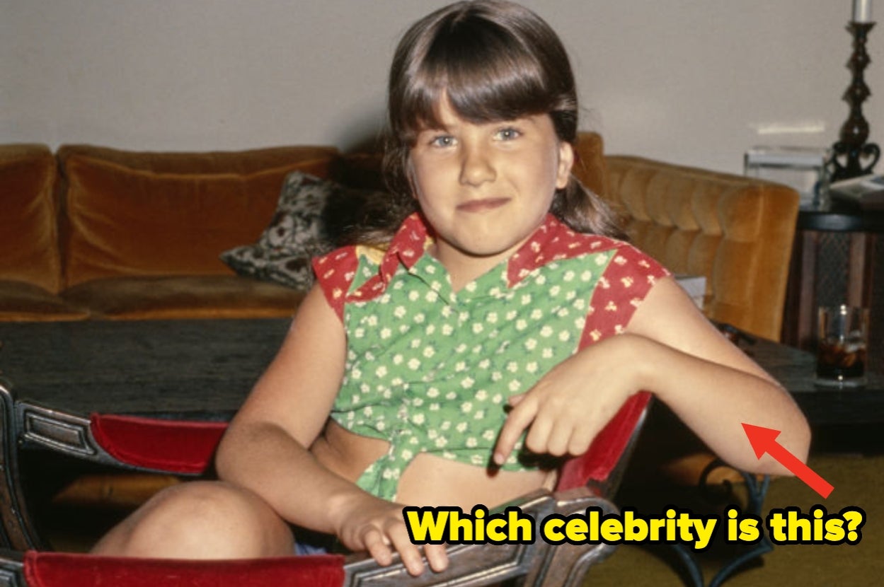 Young girl sitting on a chair indoors, smiling and wearing a green and red top. Text asks which celebrity she is