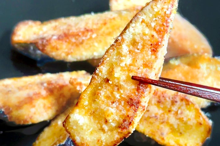 焼いたサツマイモのスライスが箸で持ち上げられている。プレート上に数切れ盛られている。