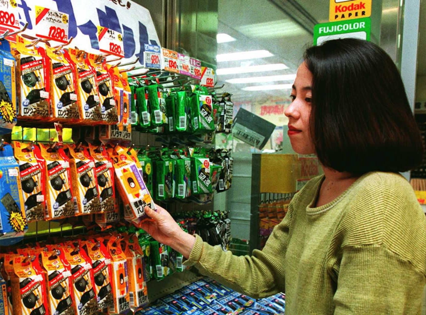 A person in a store looking at a shelf stocked with disposable cameras
