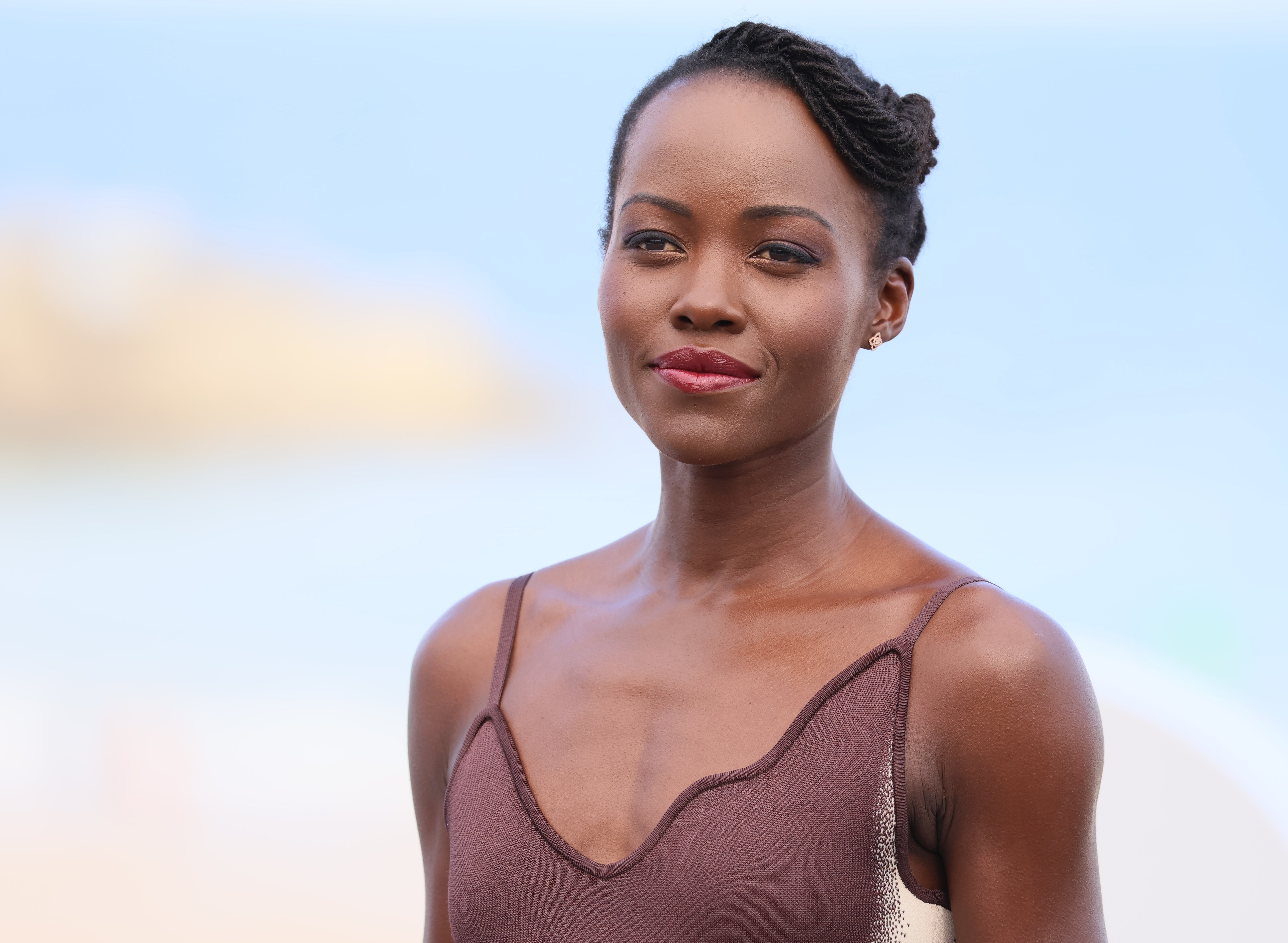 Unknown person in a sleeveless dress at an outdoor event, with hair styled in twists