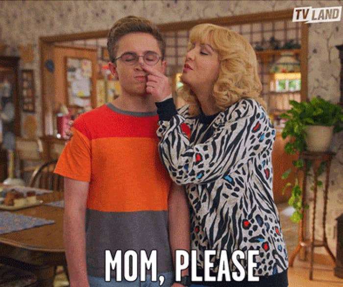 Woman successful  patterned overgarment   pinches the feature  of a young antheral   wearing glasses; substance   reads "Mom, please."