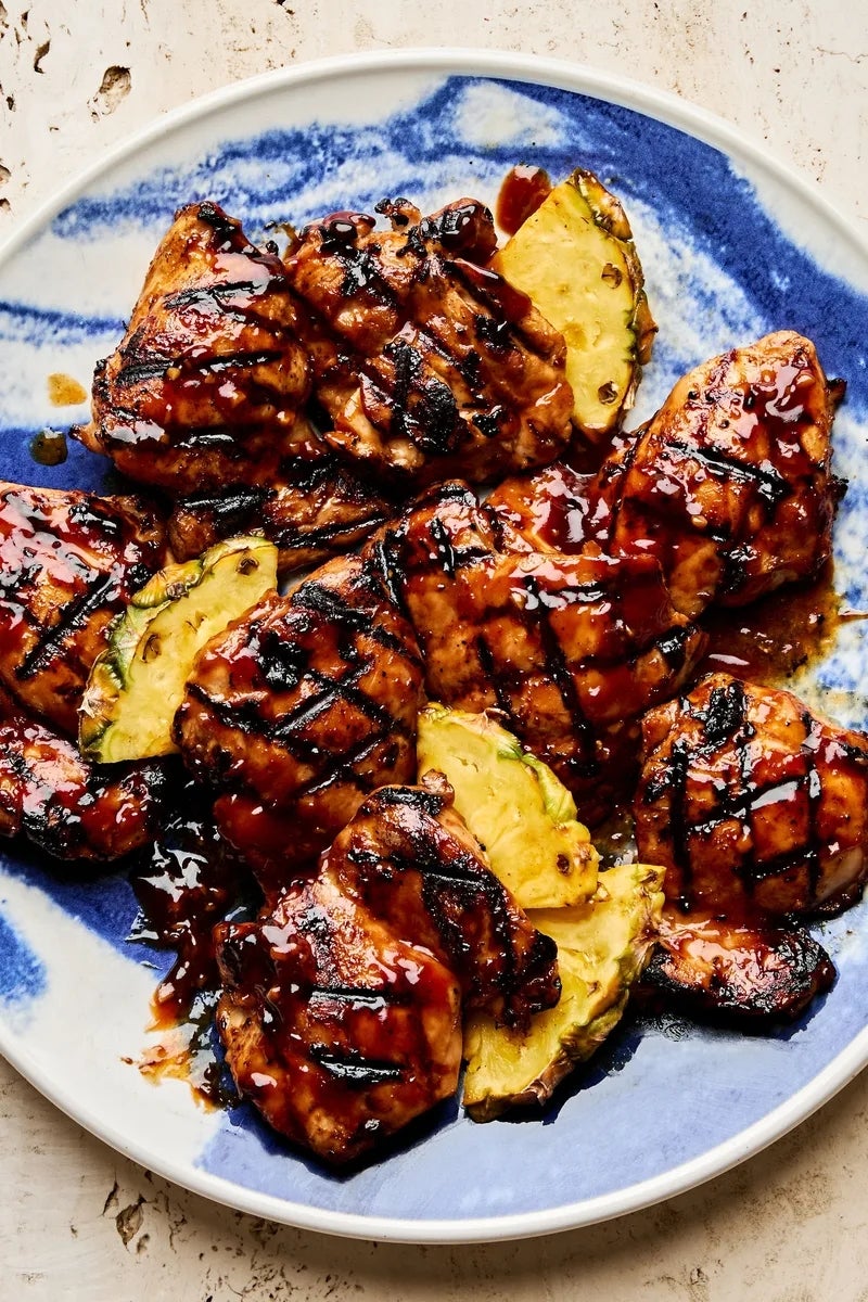 Grilled chicken thighs with barbecue glaze, garnished with pineapple slices, on a plate