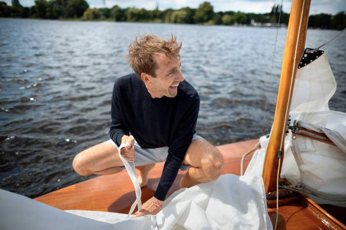 Person joyfully sailing, kneeling connected  a boat, holding a rope. The mounting  is simply a calm lake, suggesting a relaxed outdoor enactment   for well-being