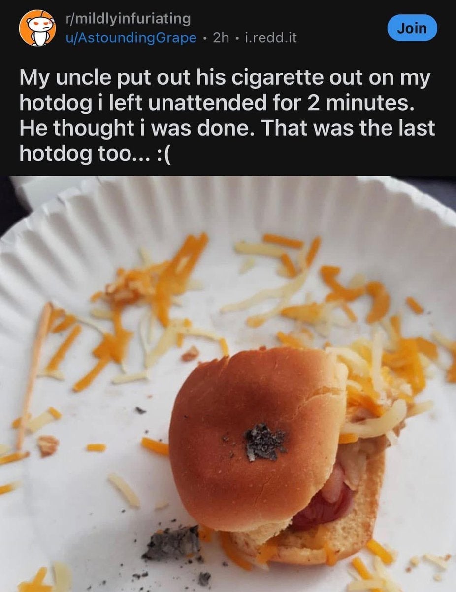 A hotdog on a plate has a cigarette butt on it, with cheese scattered around. Text above describes how it happened