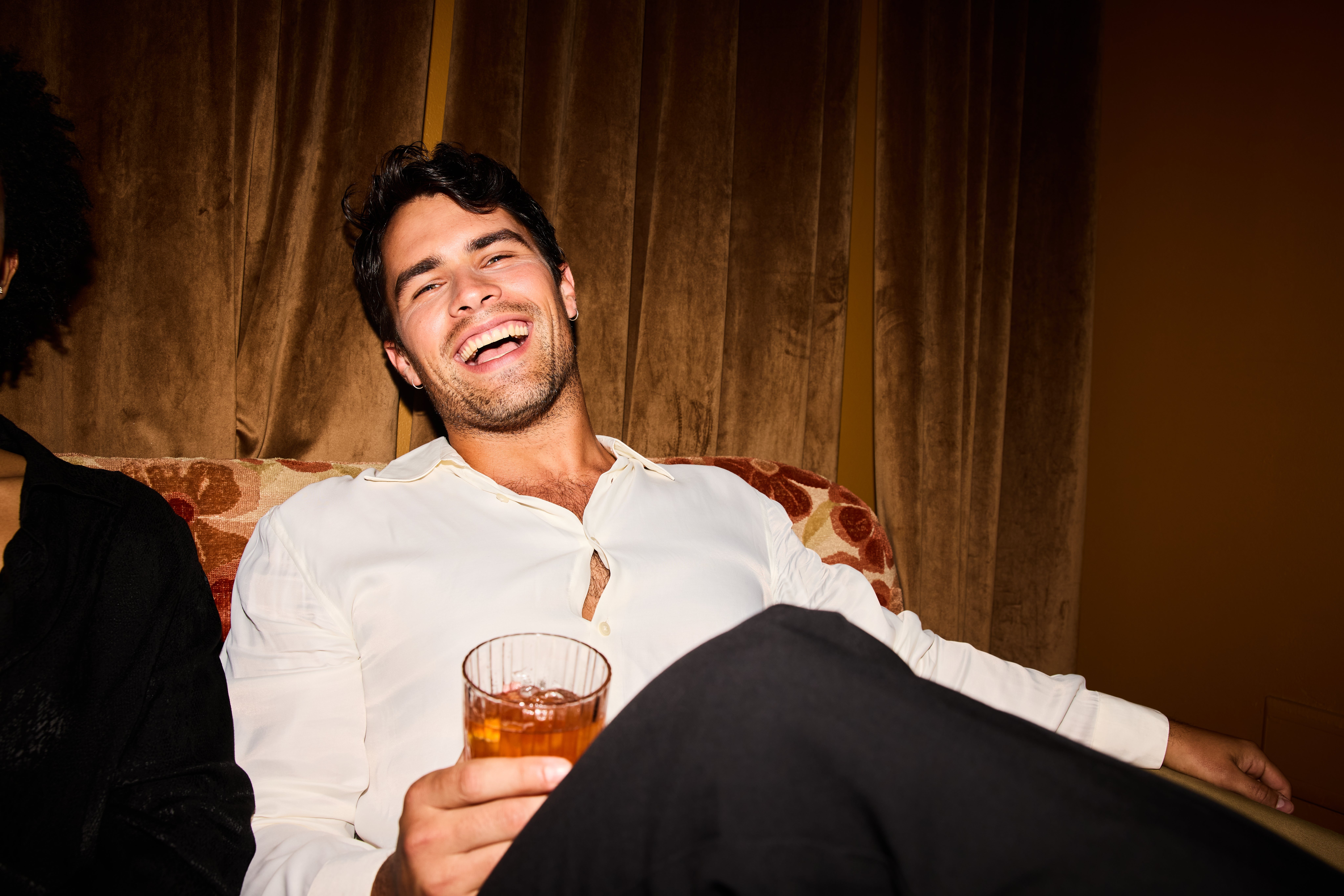 Person smiling and relaxing connected a couch, holding a drink. The mounting appears casual and joyful