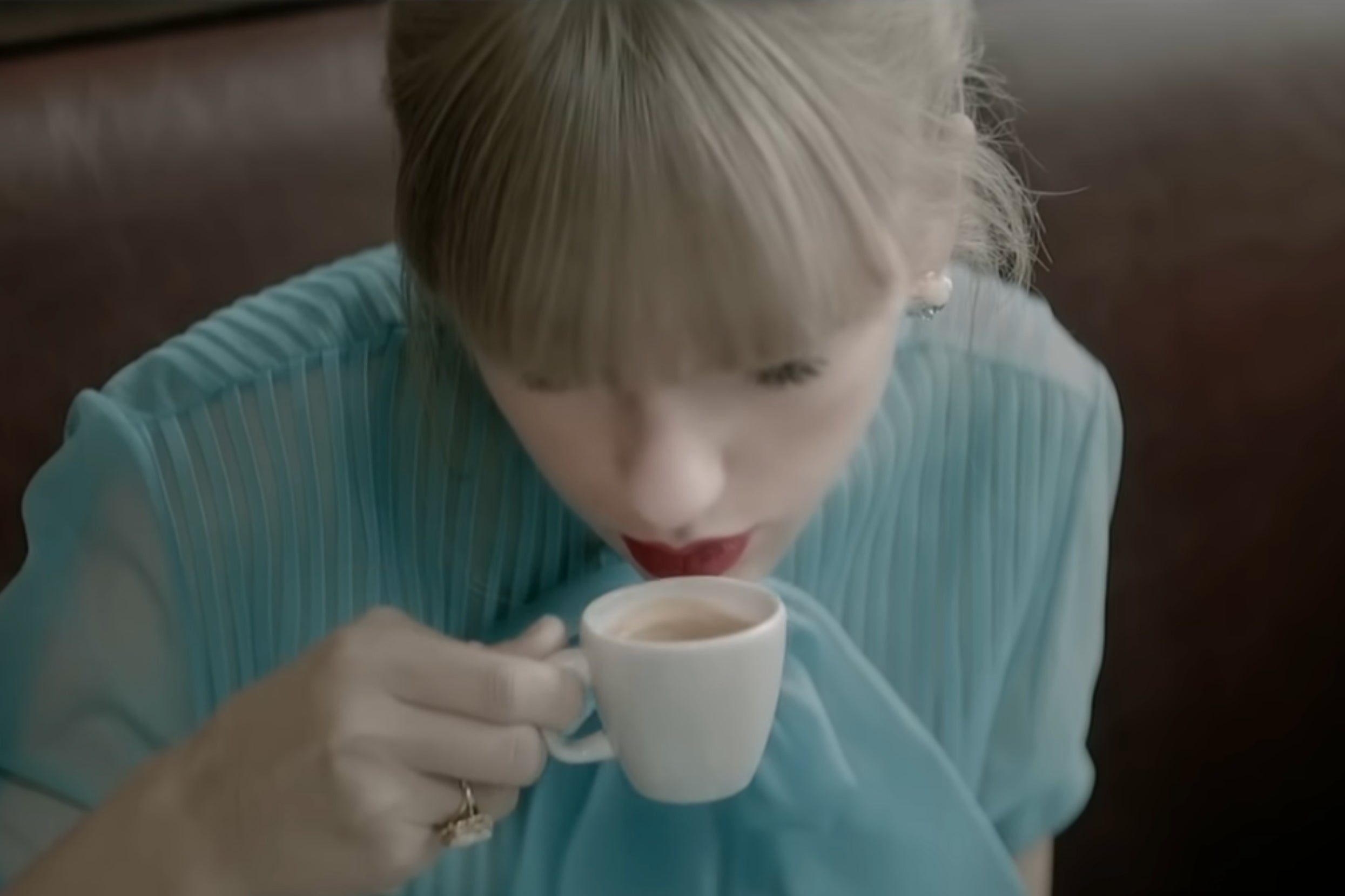 Taylor Swift sipping espresso from a small cup in the Begin Agan music video
