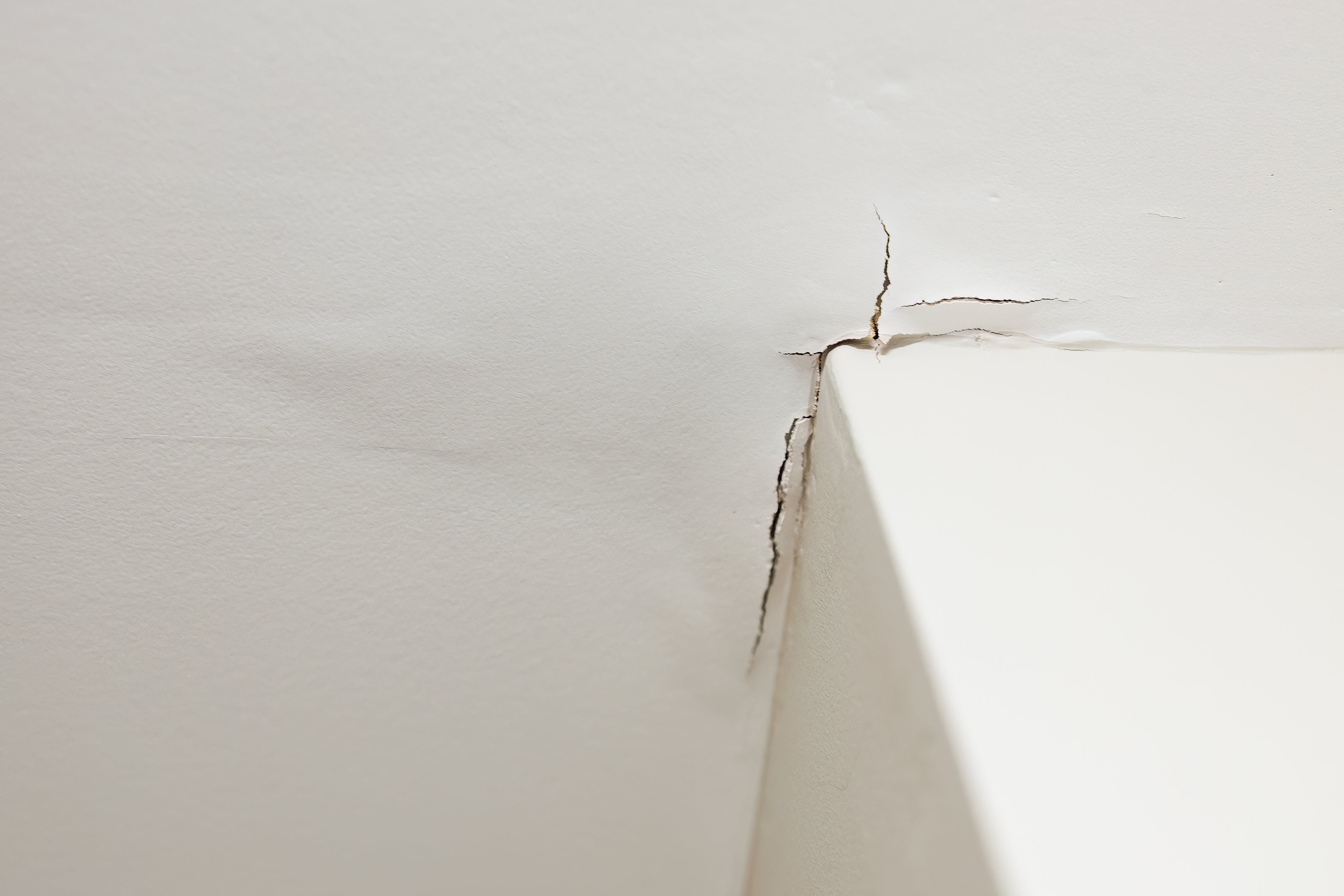 Crack in a white wall near a corner, indicating potential structural damage