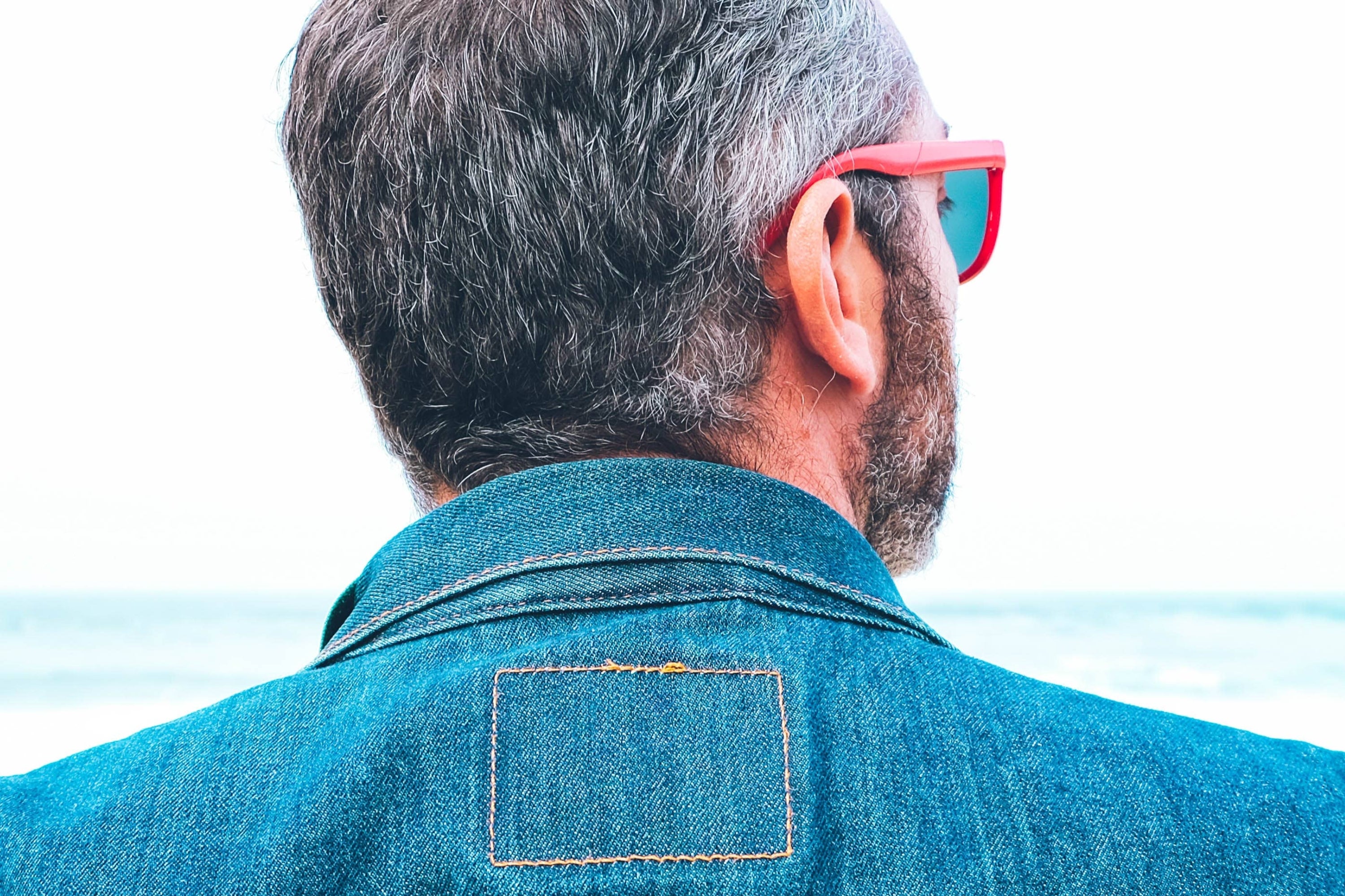 Man in sunglasses faces ocean, text overlay: "It's time to enjoy life more."