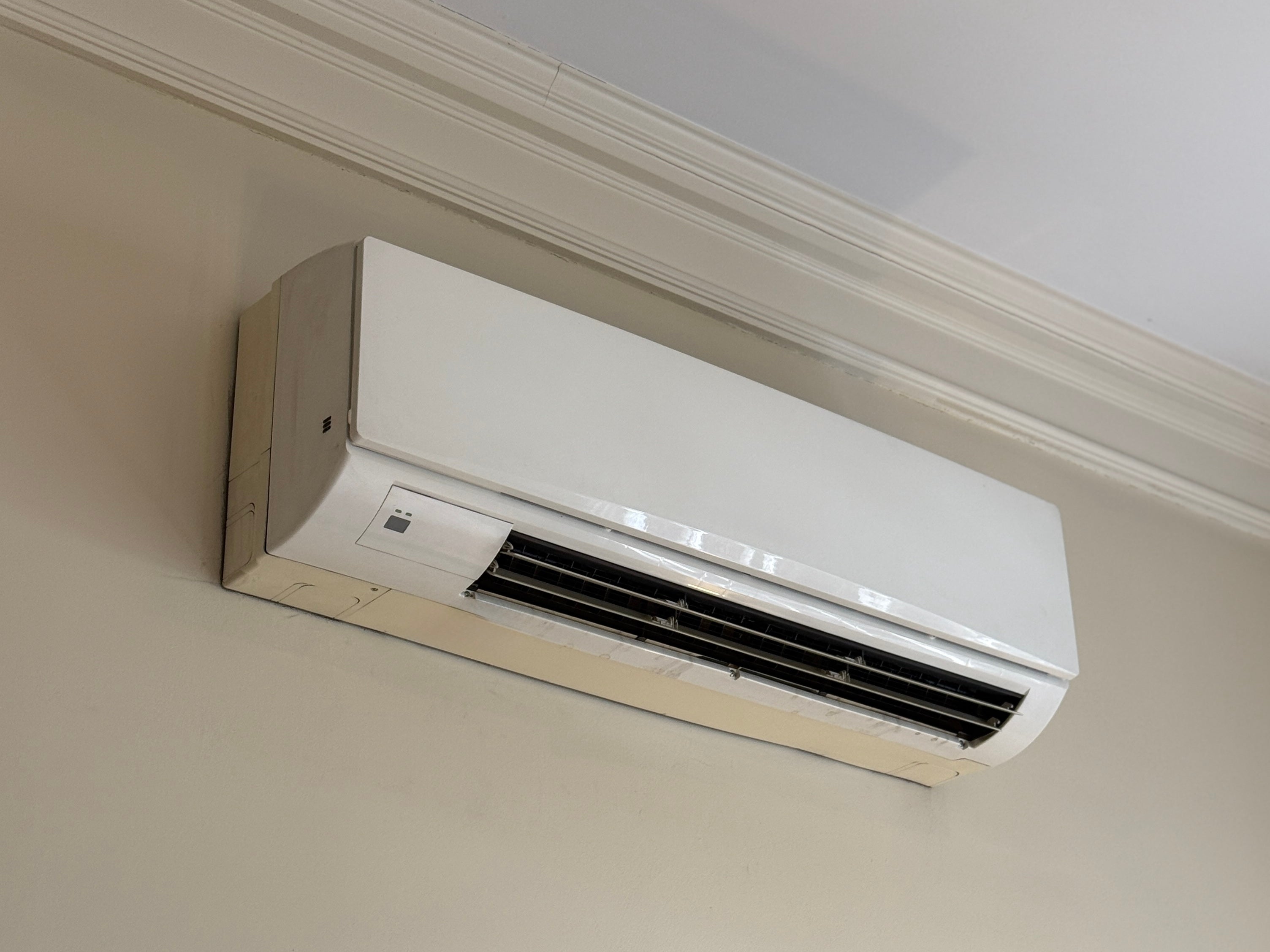 Wall-mounted air conditioning unit installed near a ceiling